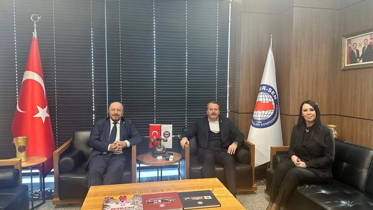 Ofis ortamında Türk bayrağı ve Memur-Sen bayrağı önünde üç kişi koltuklarda oturuyor.