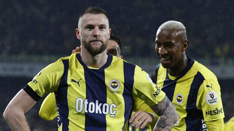 Sarı-lacivert formalı iki futbolcu sahada yan yana duruyor; öndeki oyuncu kollarını iki yana açmış.