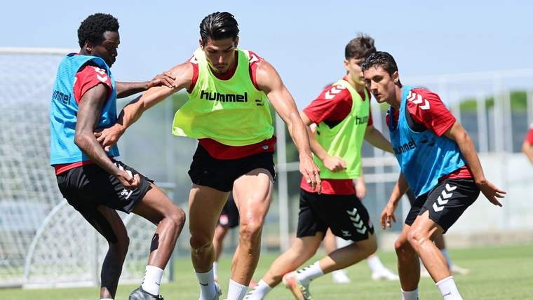Çim sahada, renkli antrenman yelekleri giyen beş futbolcu top çevresinde mücadele ediyor.