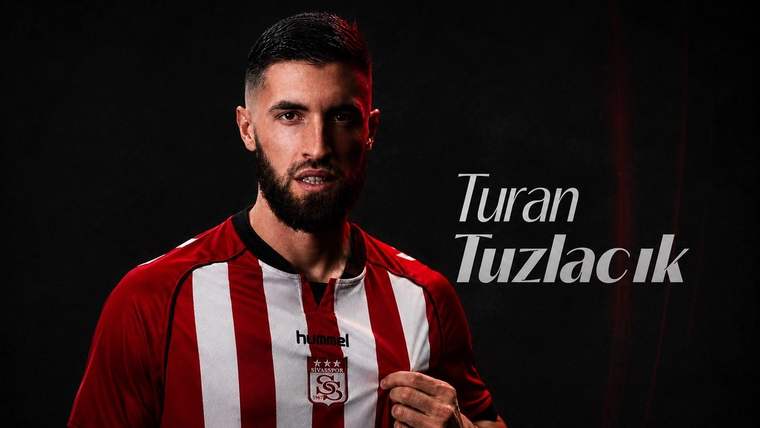 Kırmızı beyaz çubuklu forma giyen sakallı bir kişi, siyah arka plan önünde formasını tutuyor.