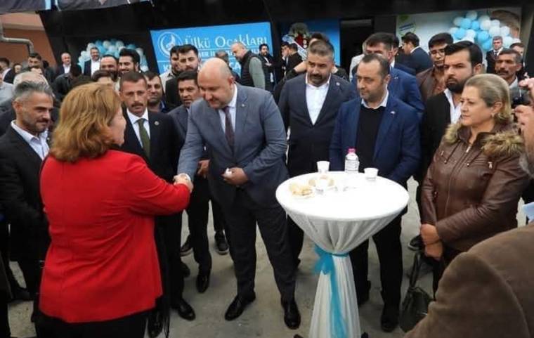 Bir grup insan, açılış etkinliğinde birbirleriyle selamlaşıyor.