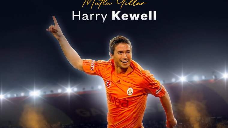 Turuncu formalı bir futbolcu, stadyumda havaya sıçrayarak bir elini kaldırıyor; üstte Harry Kewell yazıyor.