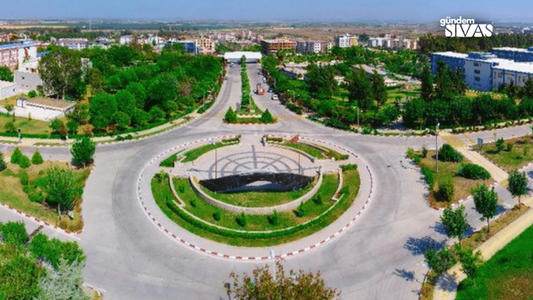 Bir kavşak, ortasında çiçekler ve ağaçlarla süslenmiş bir alan var.