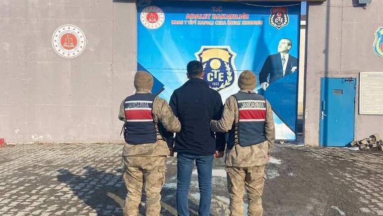 İki jandarma, kapalı ceza infaz kurumu önünde bir kişiyi tutuyor.
