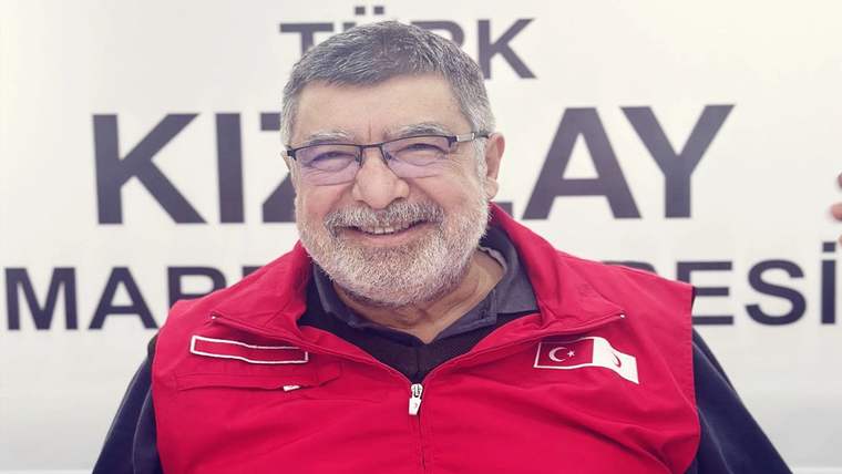 Kırmızı Kızılay montu giymiş, gülümseyen bir adam, arka planda Kızılay yazısı var.
