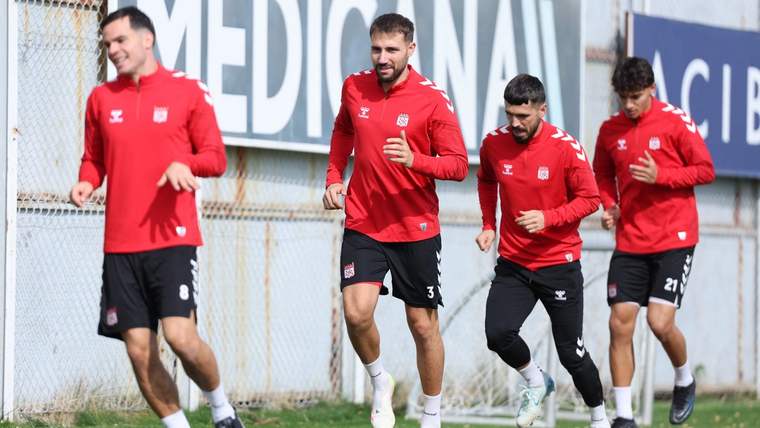 Kırmızı forma giymiş dört futbolcu, antrenman sahasında koşuyor.