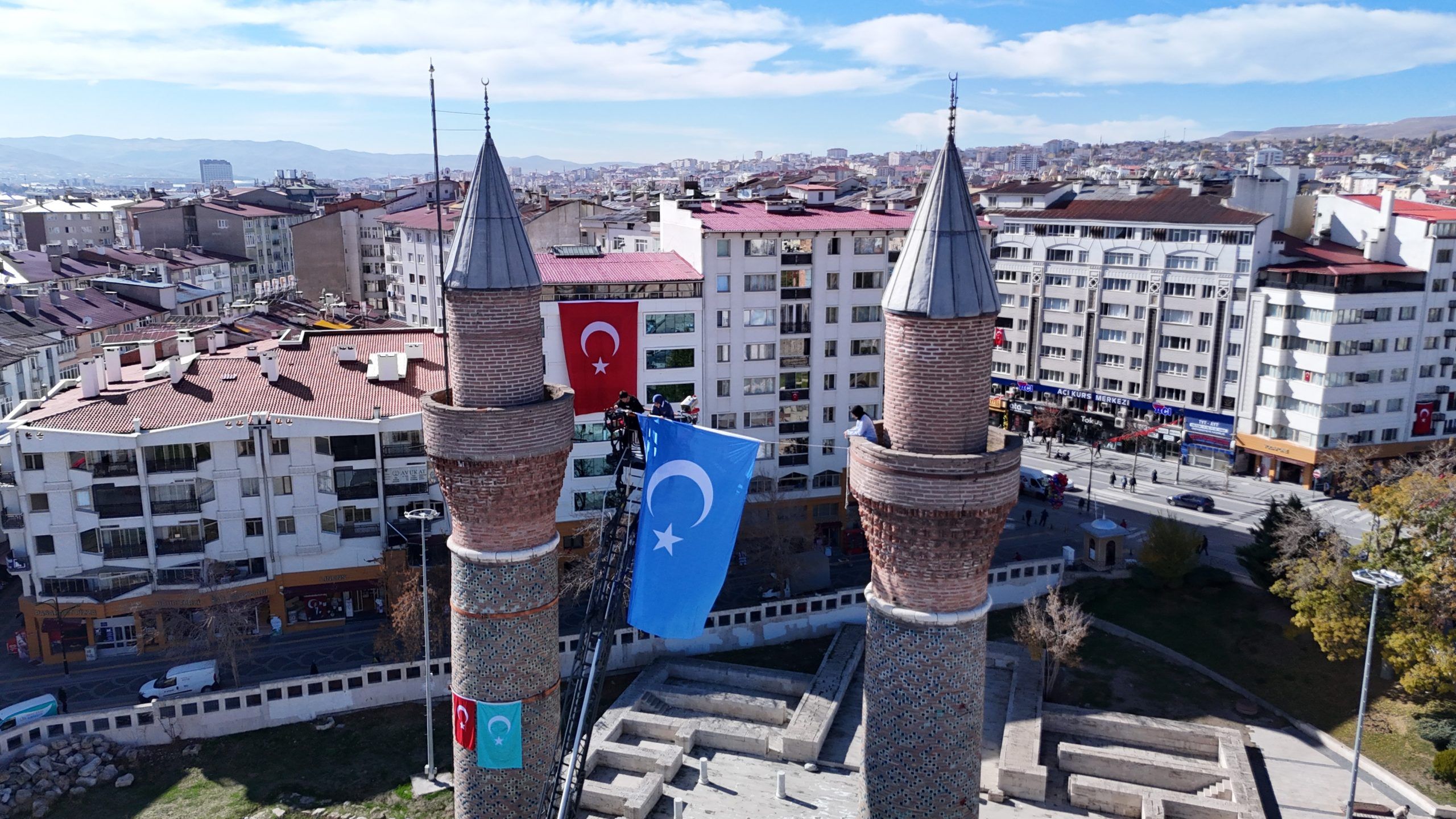 İki minaresi olan bir caminin üzerinde Türk bayrağı ve Uygur bayrağı asılı.