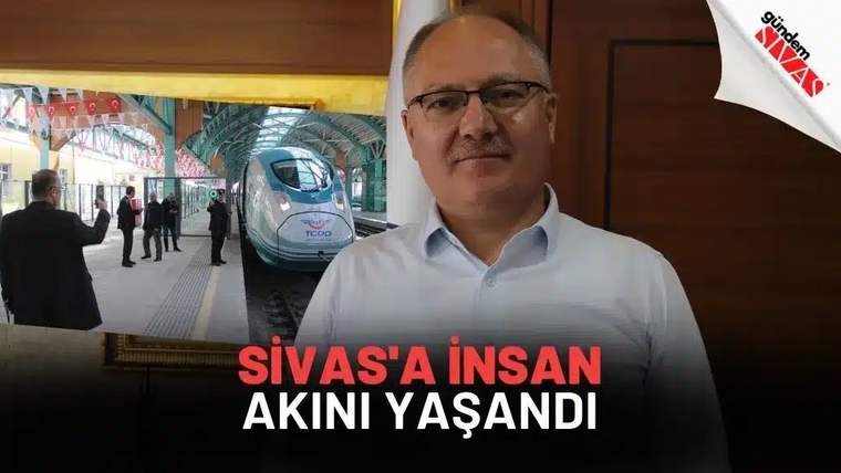 Bir kişi, arka planda yüksek hızlı trenin bulunduğu bir istasyonun önünde duruyor.