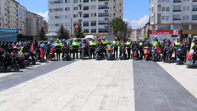 Engelli bireylerin katıldığı bir etkinlikte, elektrikli scooter kullanan kalabalık bir grup yer alıyor.