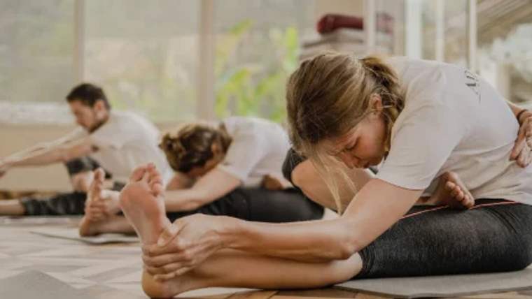 Bir grup insan, yoga matları üzerinde esneme hareketleri yapıyor.