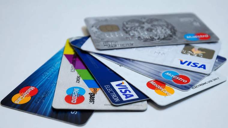 Üst üste duran farklı renklerde kredi kartlarında Visa, Mastercard ve American Express logoları görülüyor.