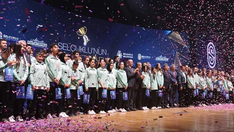 Ödül töreninde, sporcular sahnede duruyor, etraflarında konfeti yağıyor.