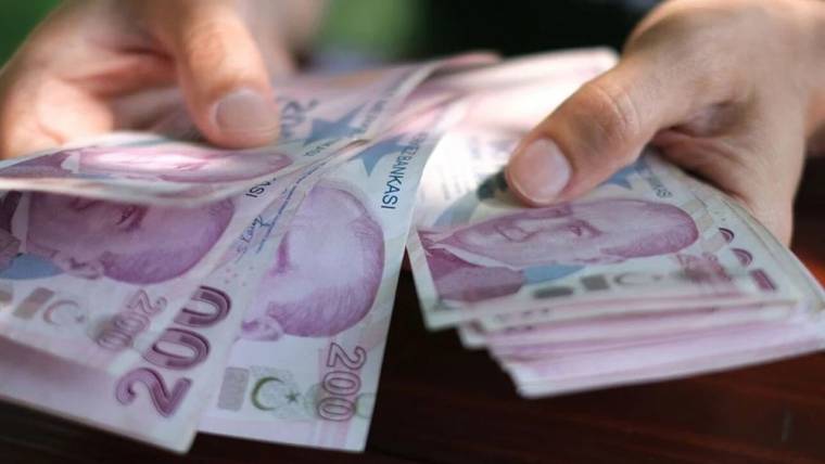 Eller, ahşap yüzey üzerinde Türk lirası banknotlarını sayarken 200 liralık kupürler öne çıkıyor.