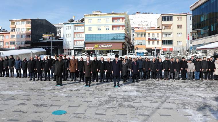 Kar ve buzla kaplı meydanda, önünde sıralanmış çok sayıda kişi ve arkada şehir binaları görülüyor.