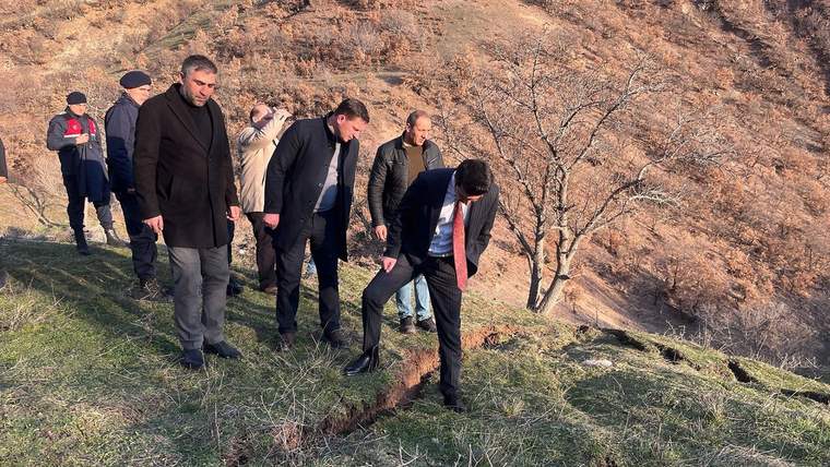Bir grup insan, Koyulhisar'da toprak kaymasının olduğu alanda inceleme yapıyor.