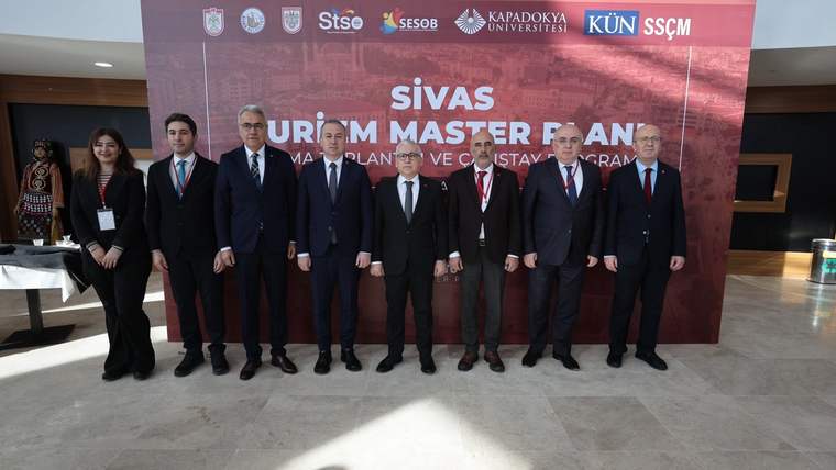 “Sivas Turizm Master Planı” yazılı pankart önünde, takım elbiseli sekiz kişi yan yana duruyor.