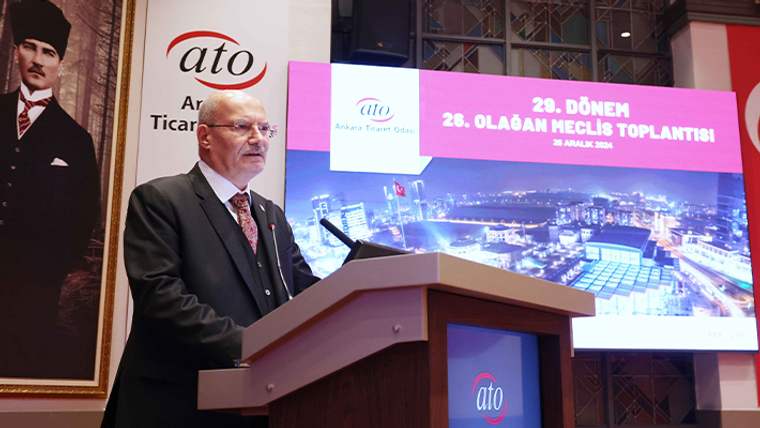 Bir kişi, bir podiumda konuşma yapıyor; arka planda ATO logosu ve toplantı bilgileri yer alıyor.