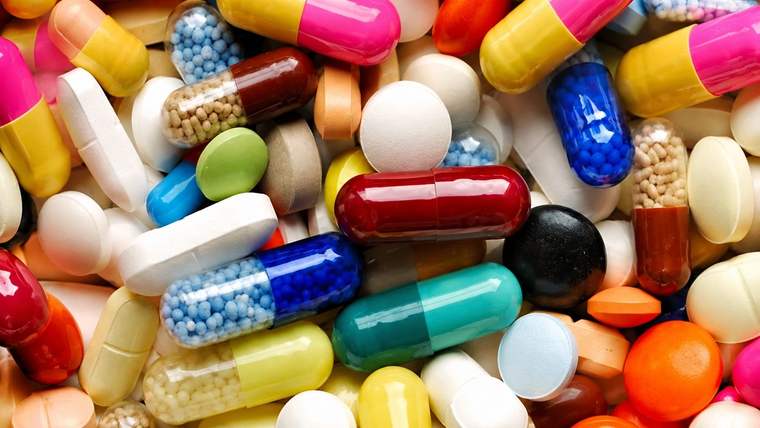 Çeşitli renk ve biçimlerde kapsül, tablet ve drajelerin birbirinin üzerine dizildiği yakın plan görünüm.