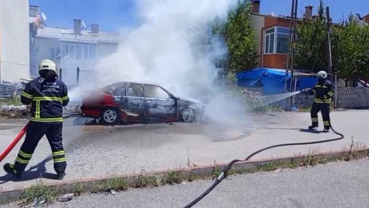 Alev alan bir Fiat marka araç, itfaiye ekipleri tarafından söndürülmeye çalışılıyor.