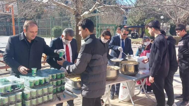 Açık alanda uzun masalarda yemek ve içecek dağıtan, çevresinde bekleyen insanların bulunduğu etkinlik