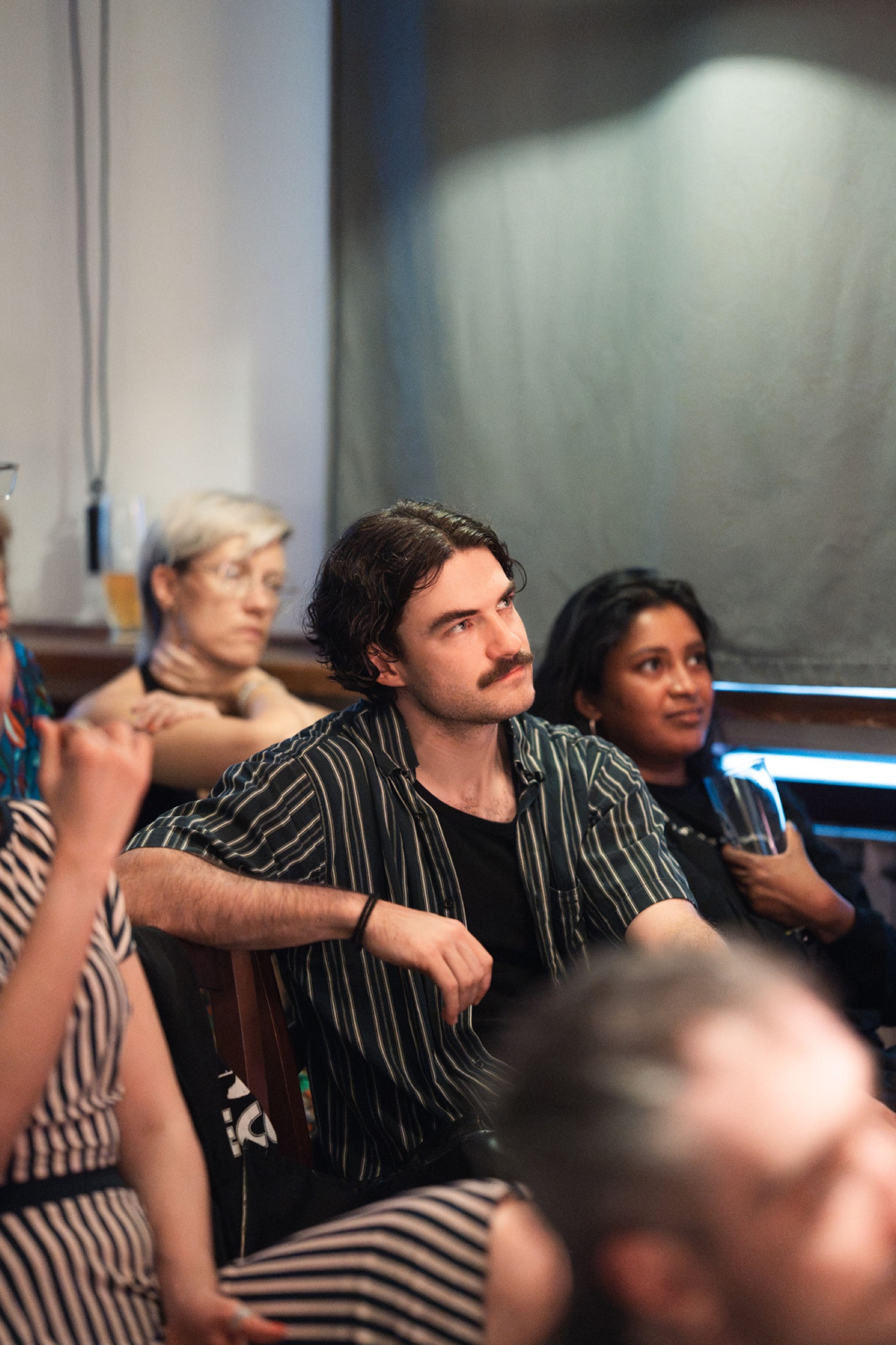 Guest in a striped shirt listening from the audience