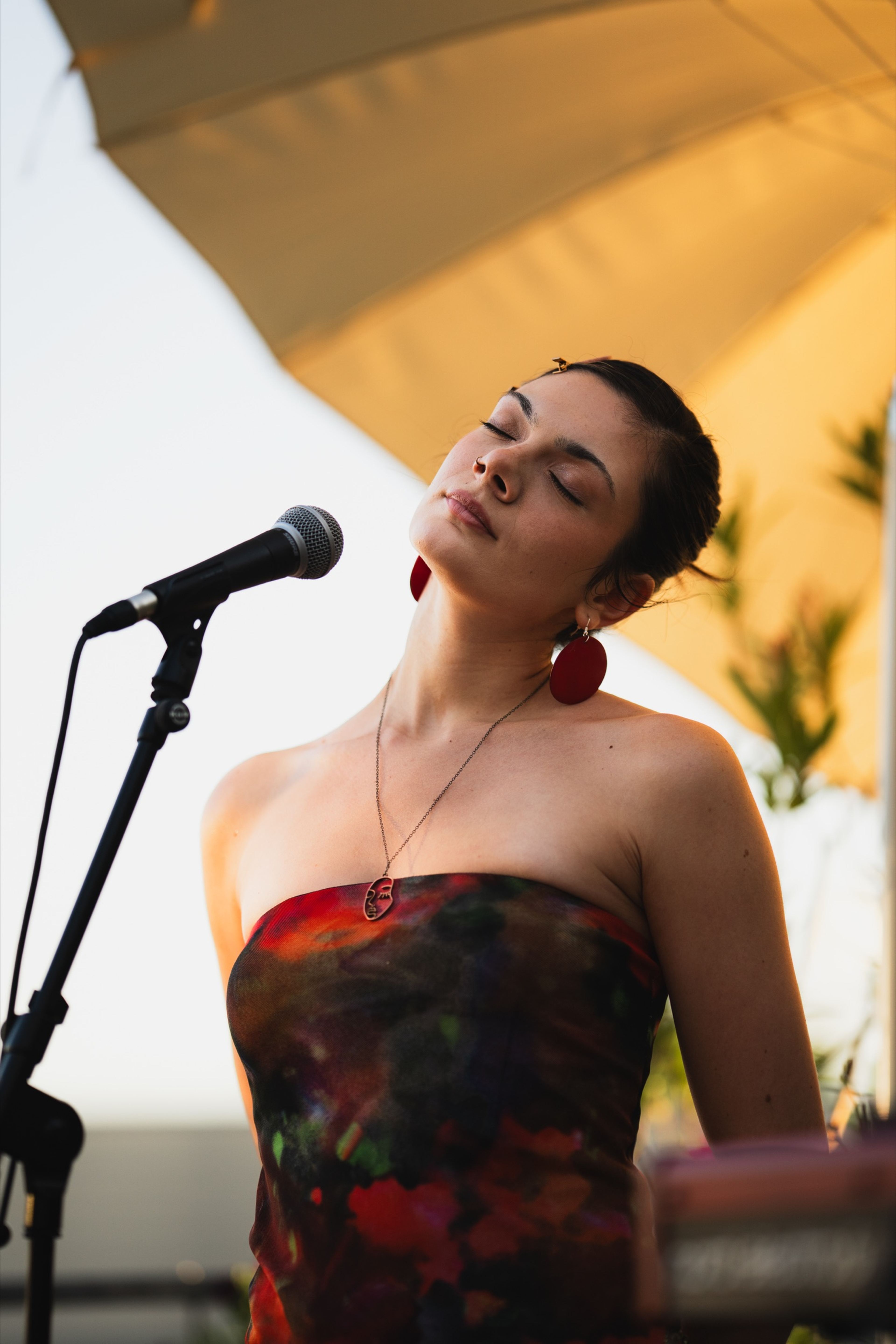 Vocalist singing with her eyes closed in golden evening light at Her Sound, a Berlin rooftop concert
