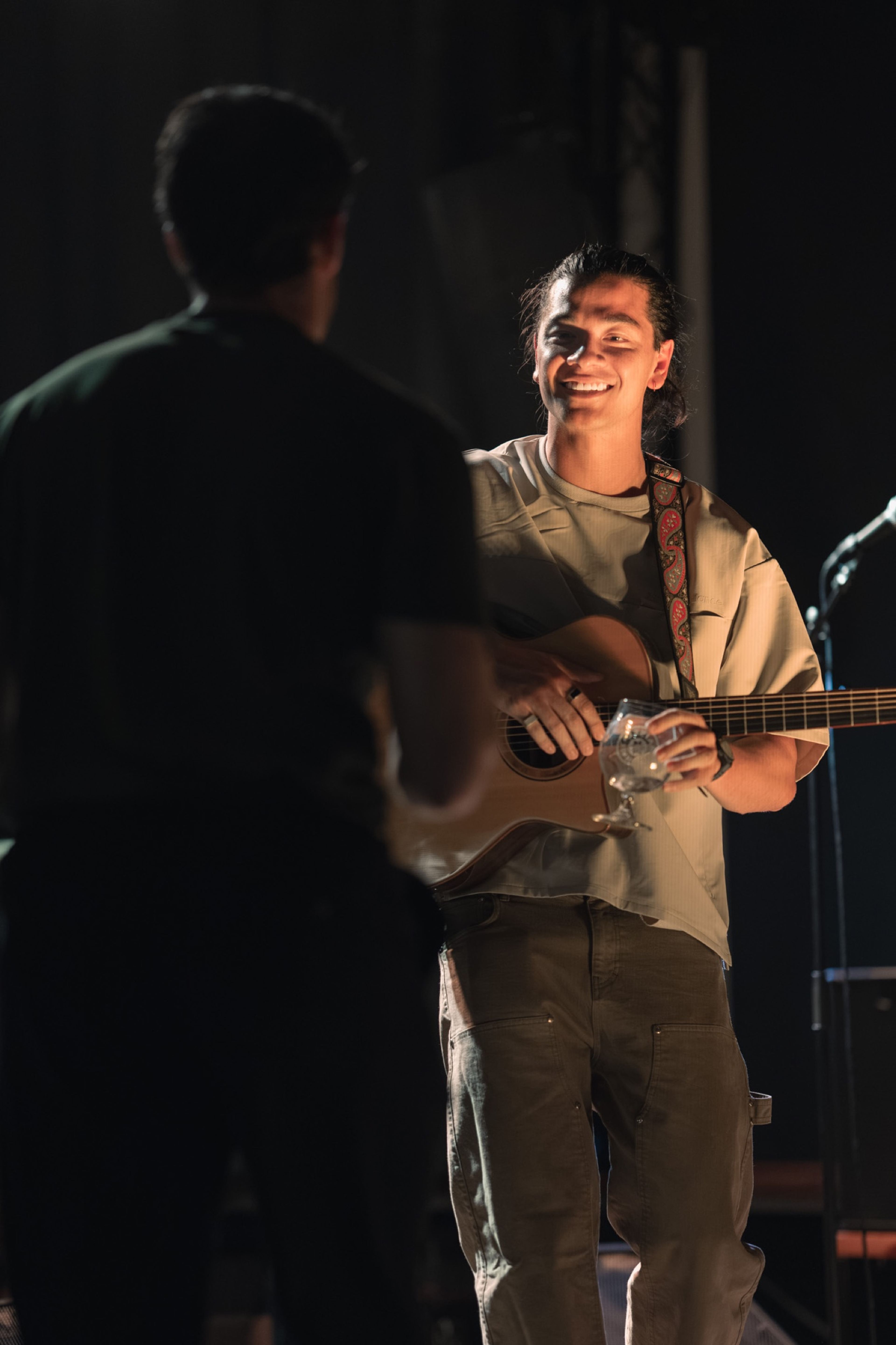 Two musicians performing at the microphone, one with a guitar