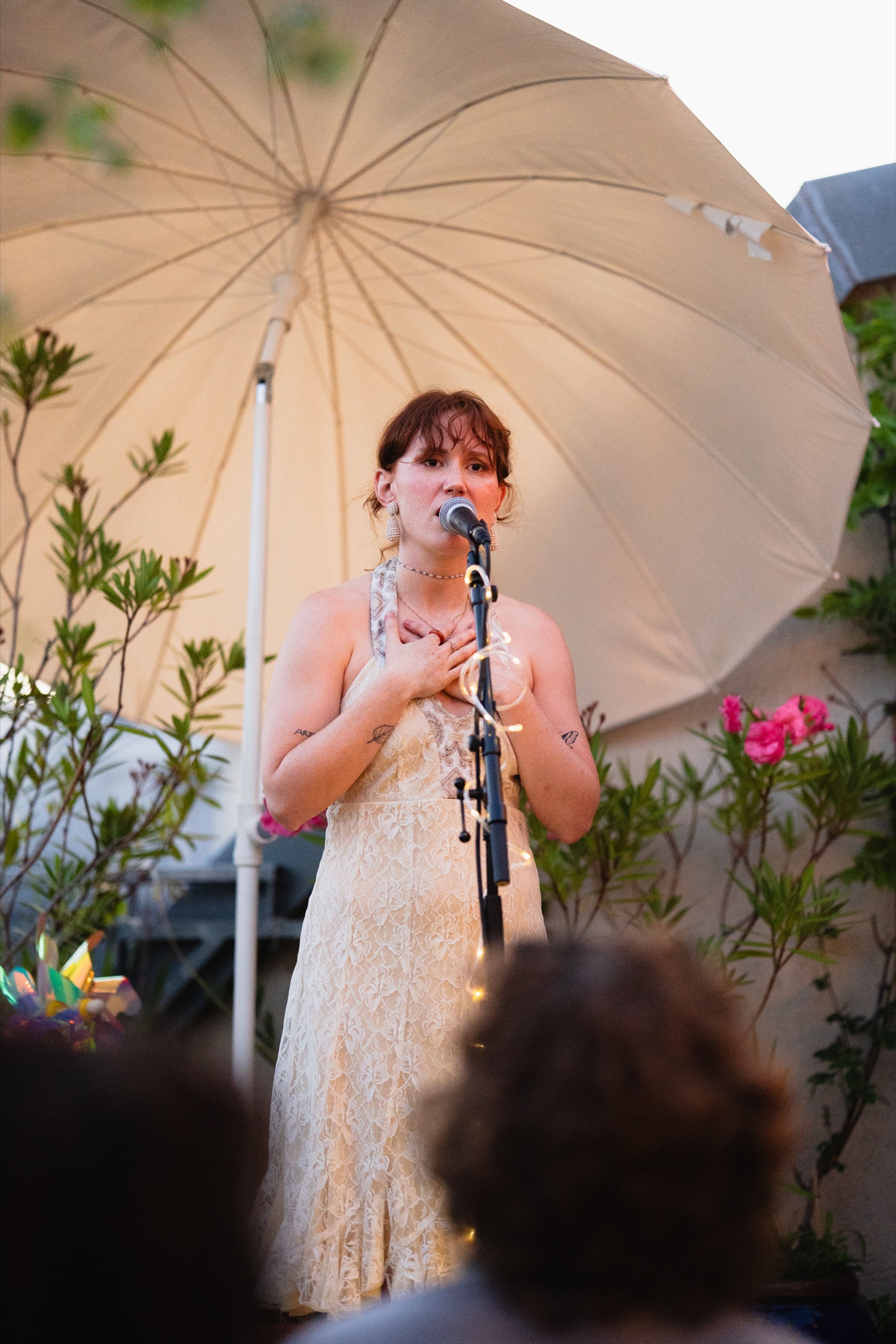 Singer with her hands on her heart during an emotional moment under a parasol