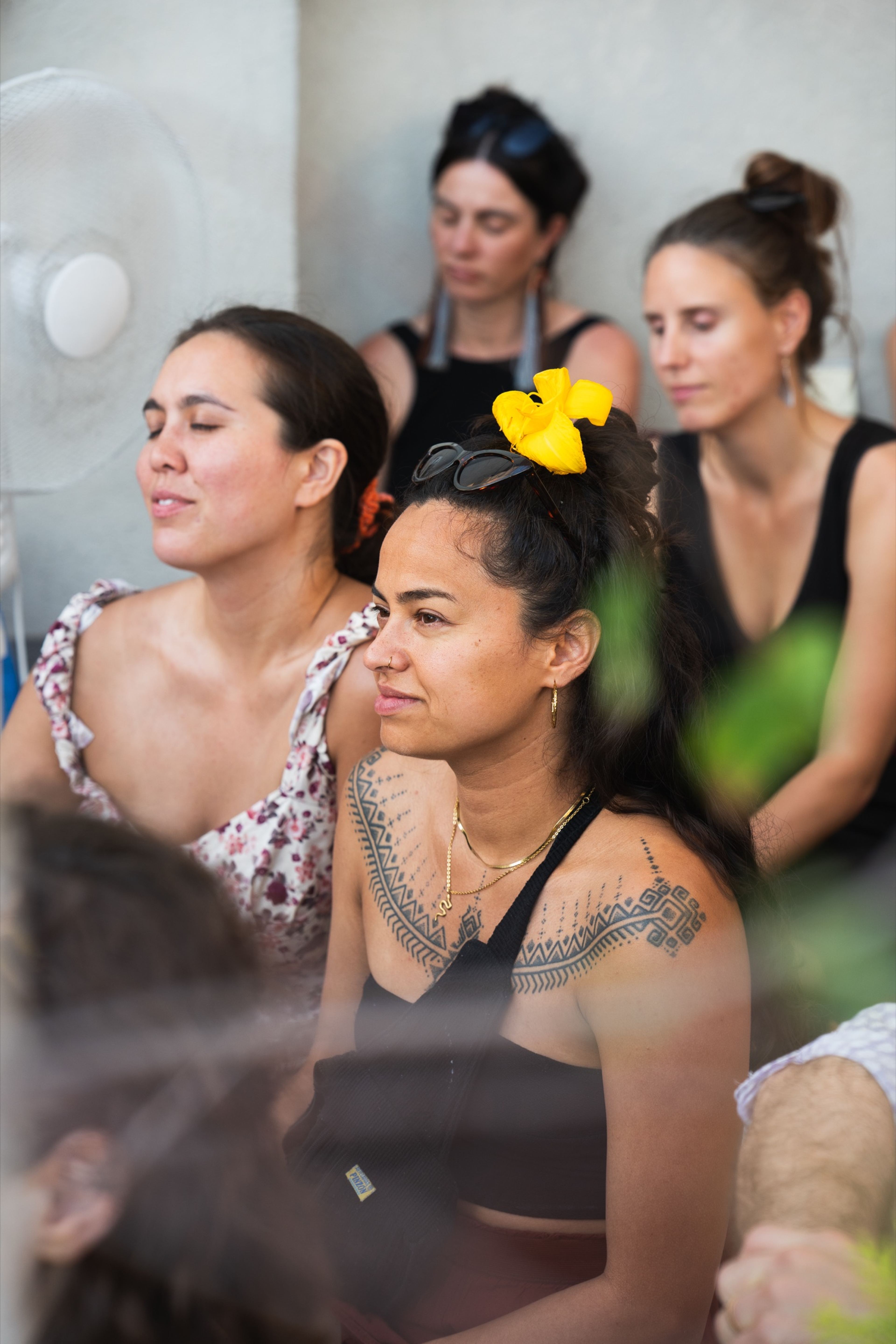 Audience member with a yellow flower in her hair listening with her eyes closed