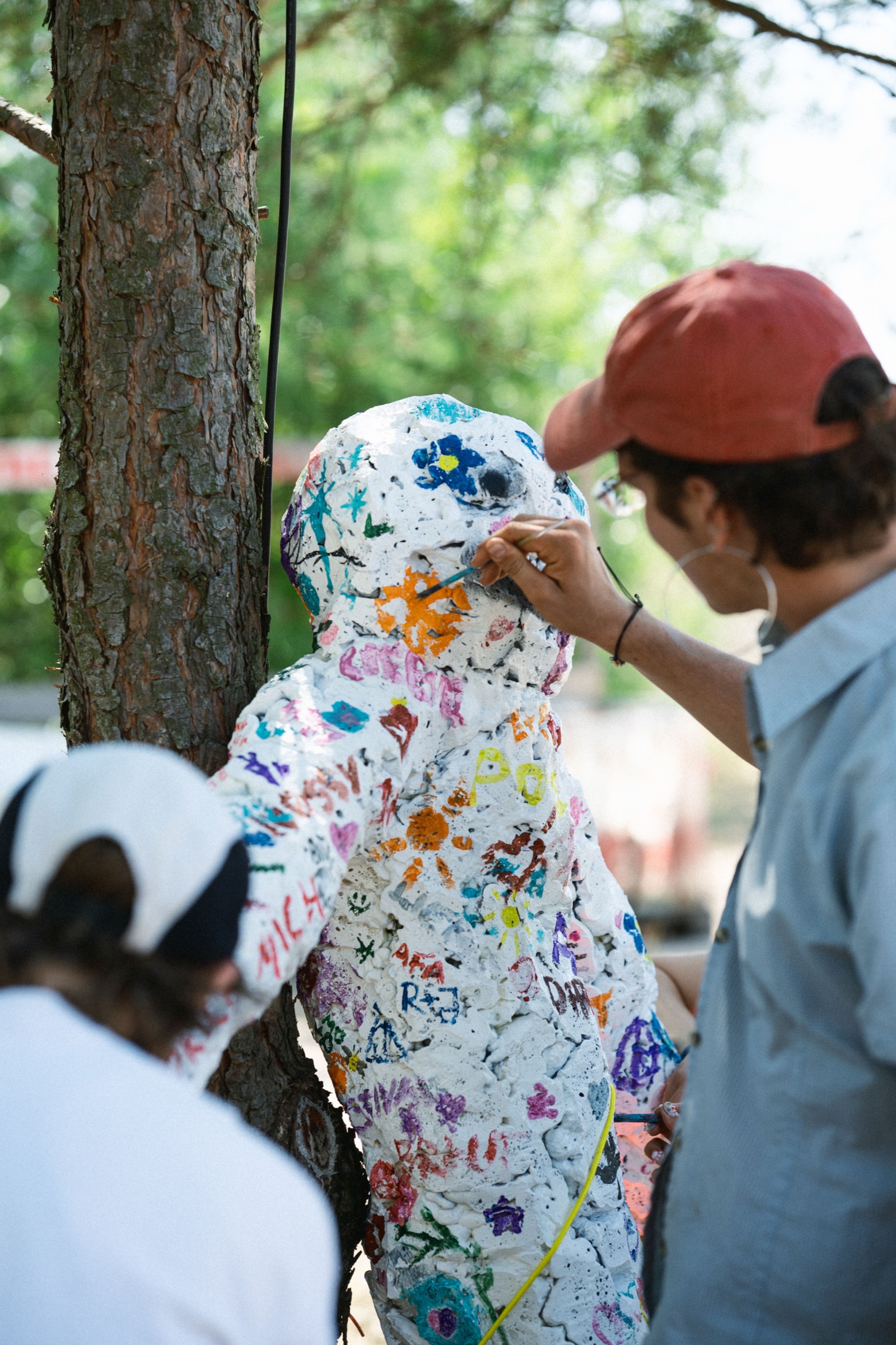 A festival-goer painting a communal sculpture covered in colourful doodles