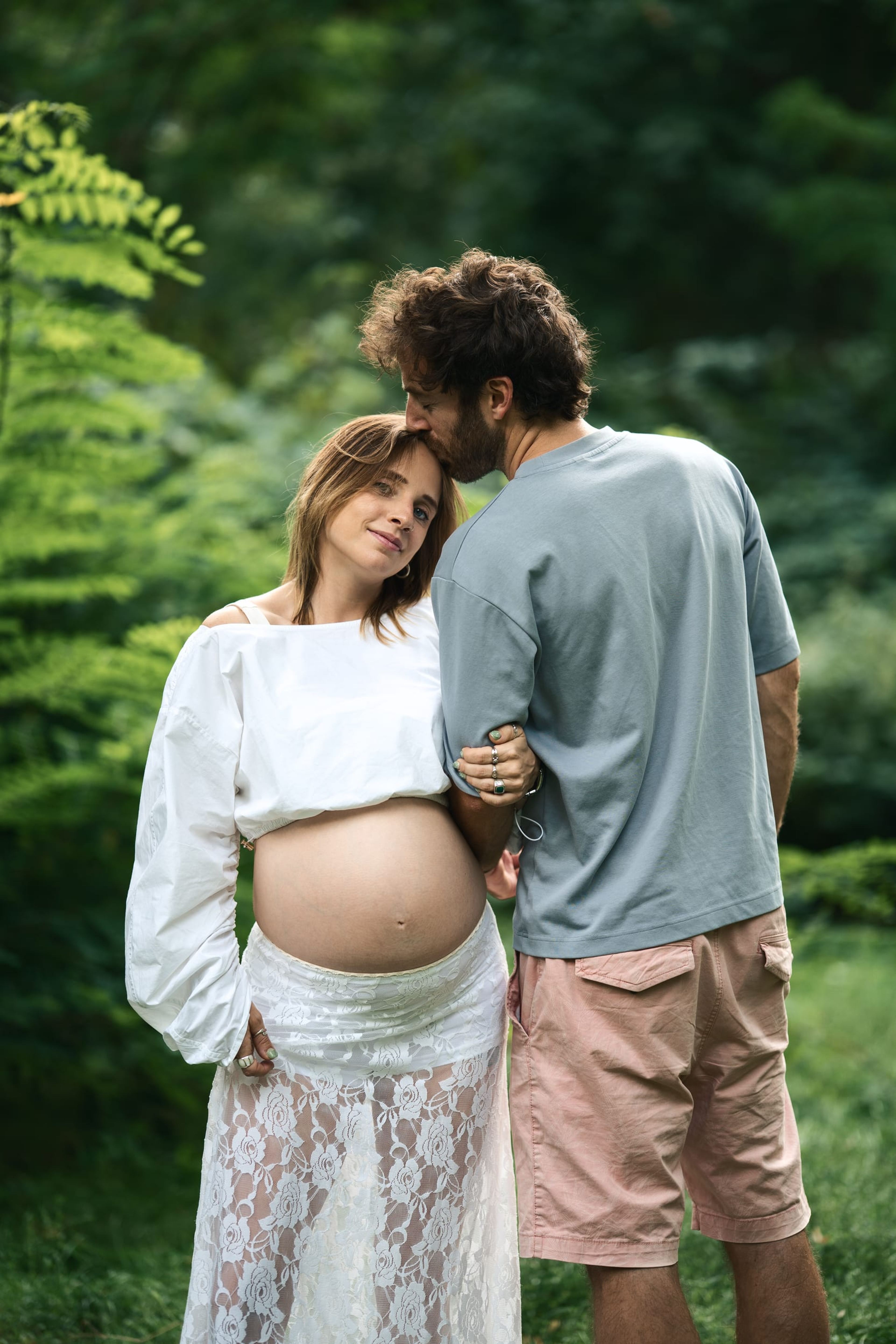 Partner kissing the expectant mother's forehead as she looks to camera