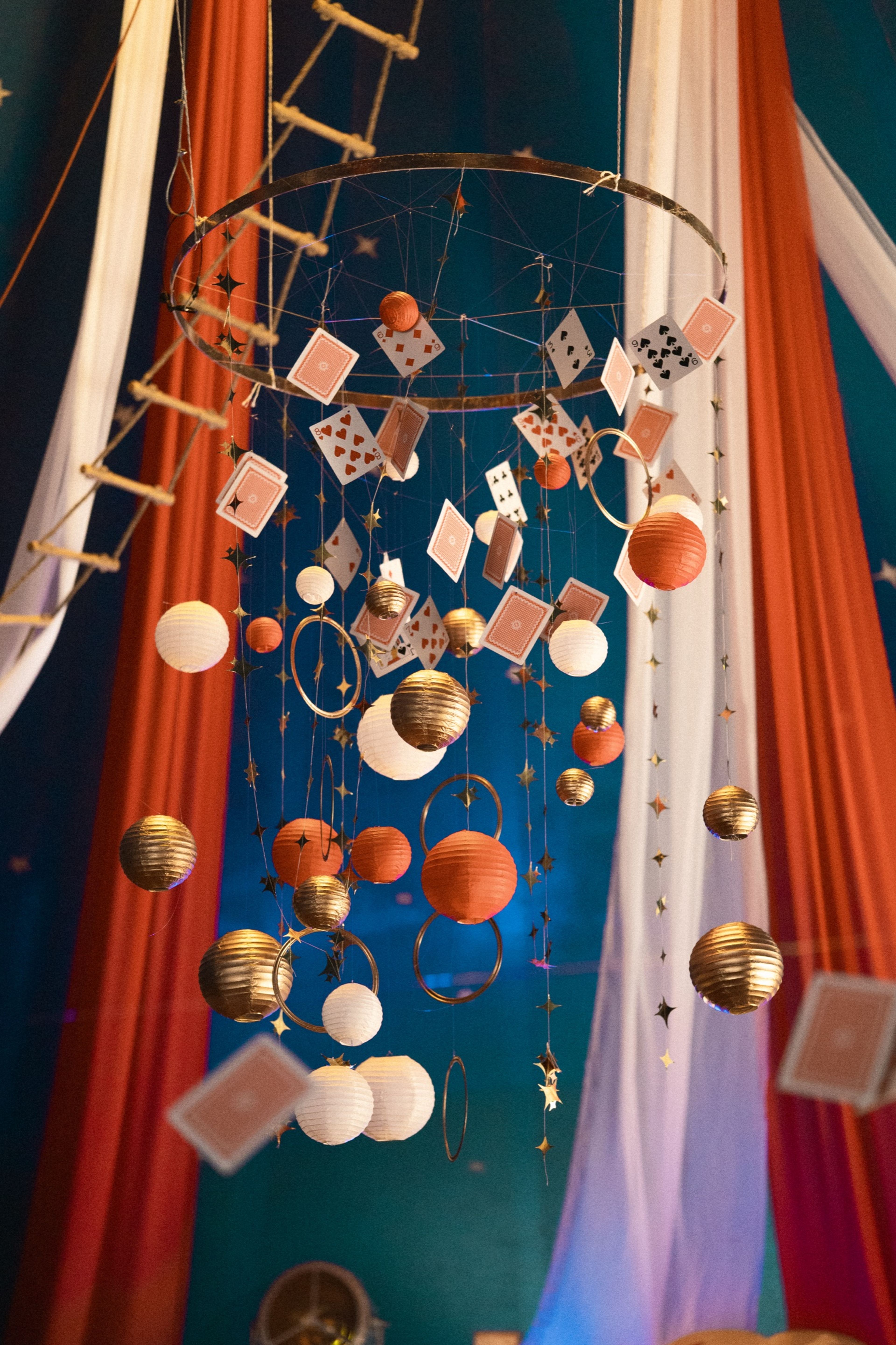 A hanging art mobile of playing cards, paper lanterns and gold stars