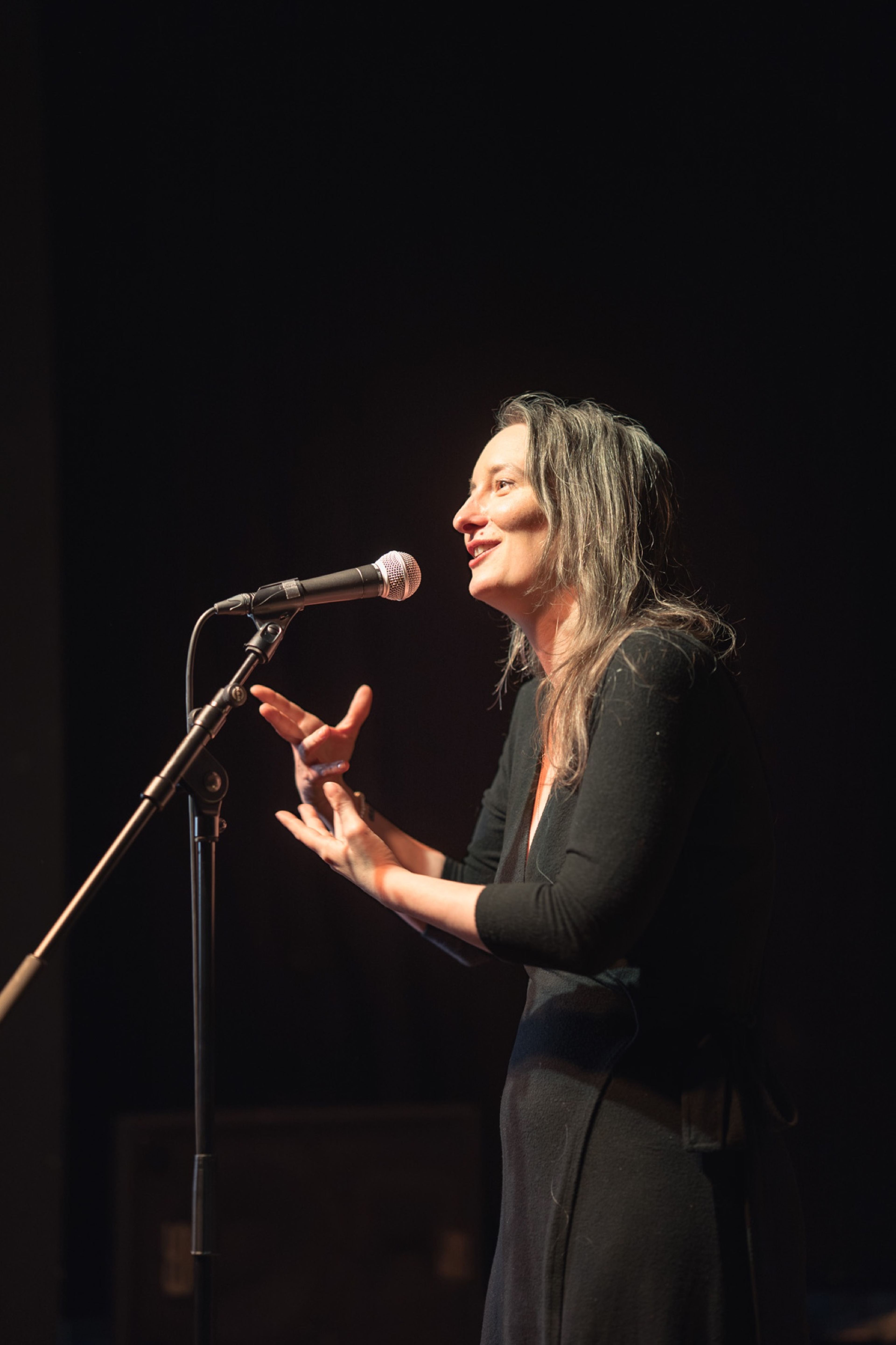 Storyteller with long hair sharing a story, hands mid-gesture