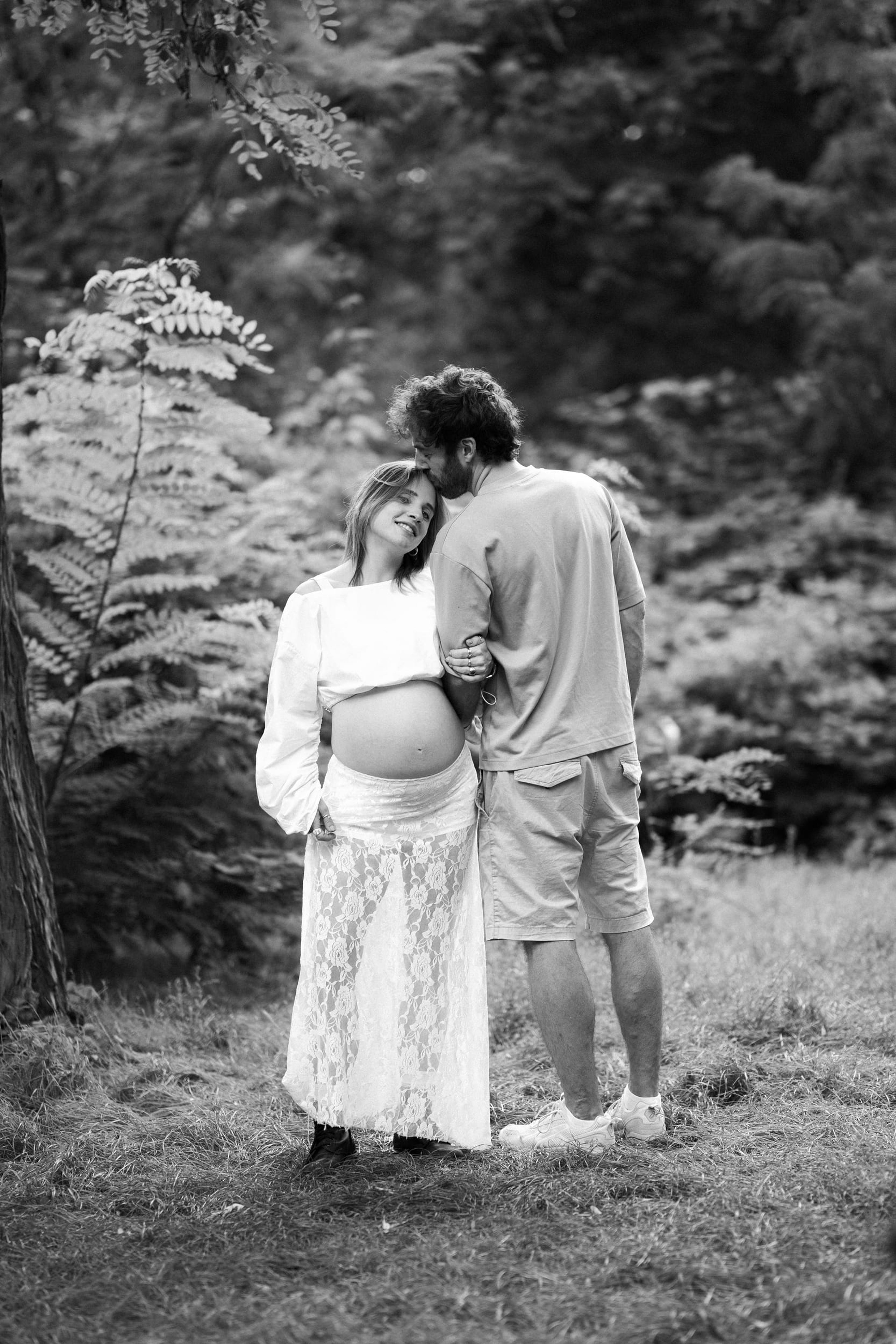 Black-and-white portrait of a partner kissing the expectant mother's forehead