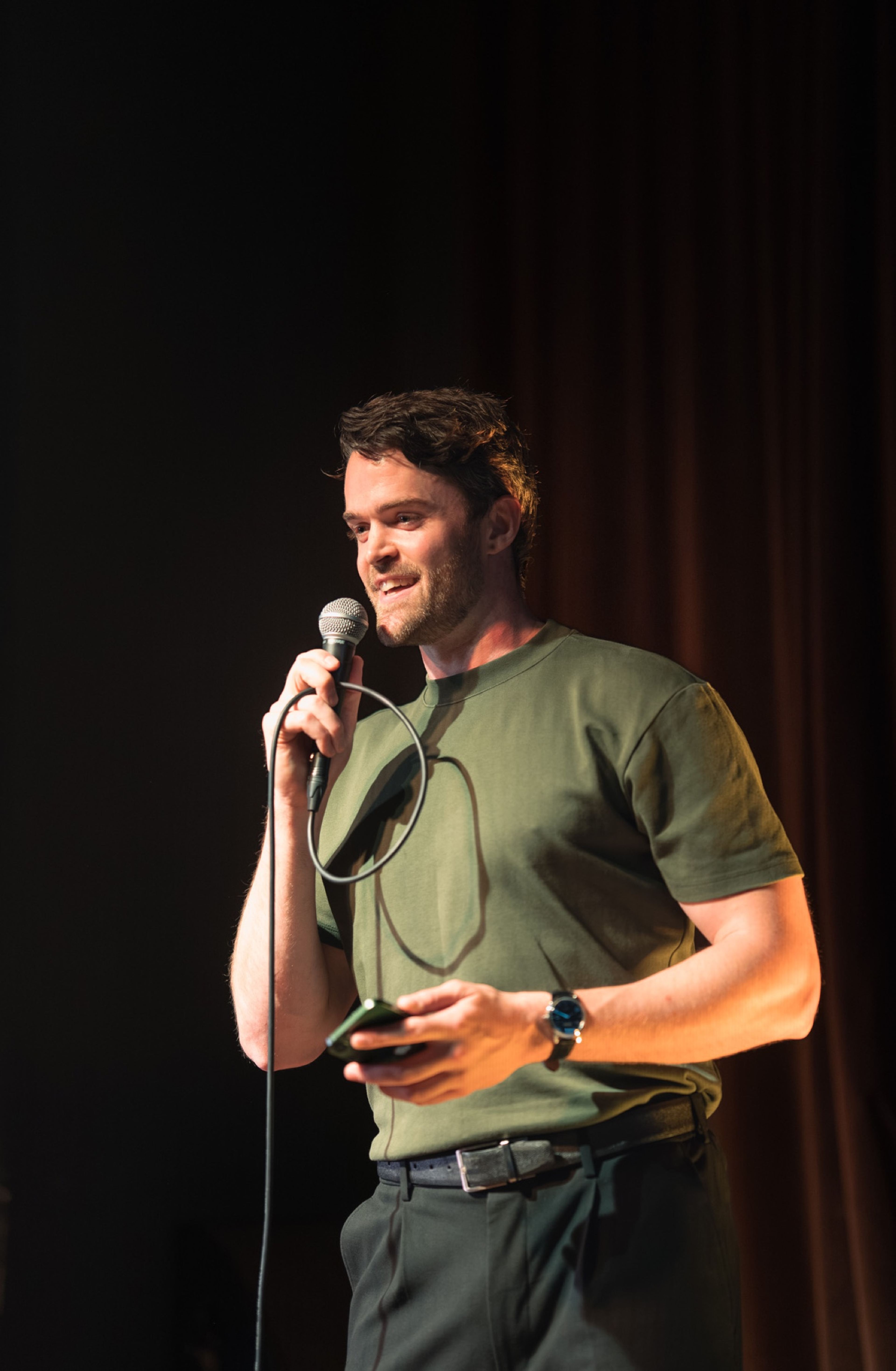 Storyteller mid-story, warmly lit against the dark stage