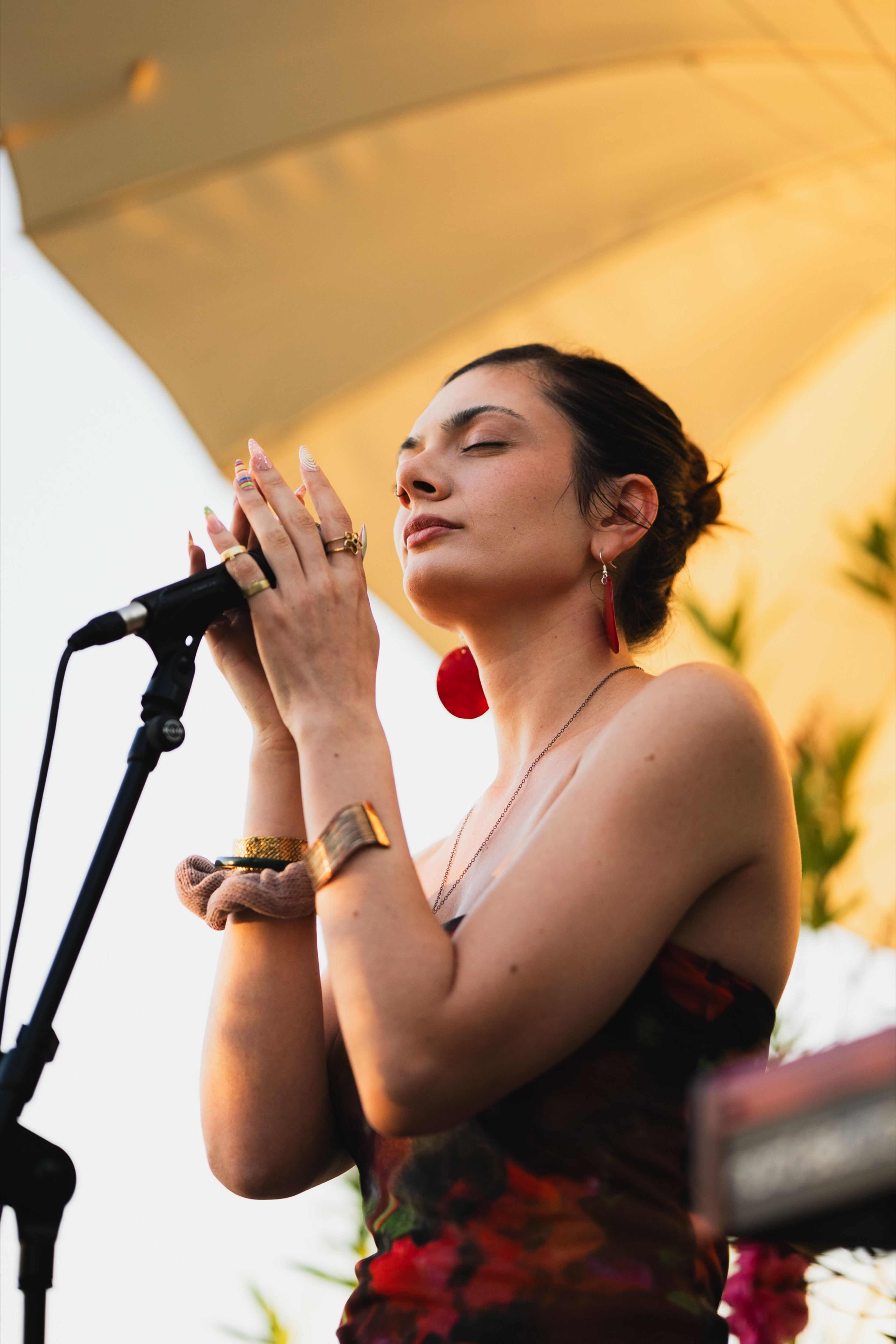 Singer cupping the microphone with her eyes closed in warm golden light