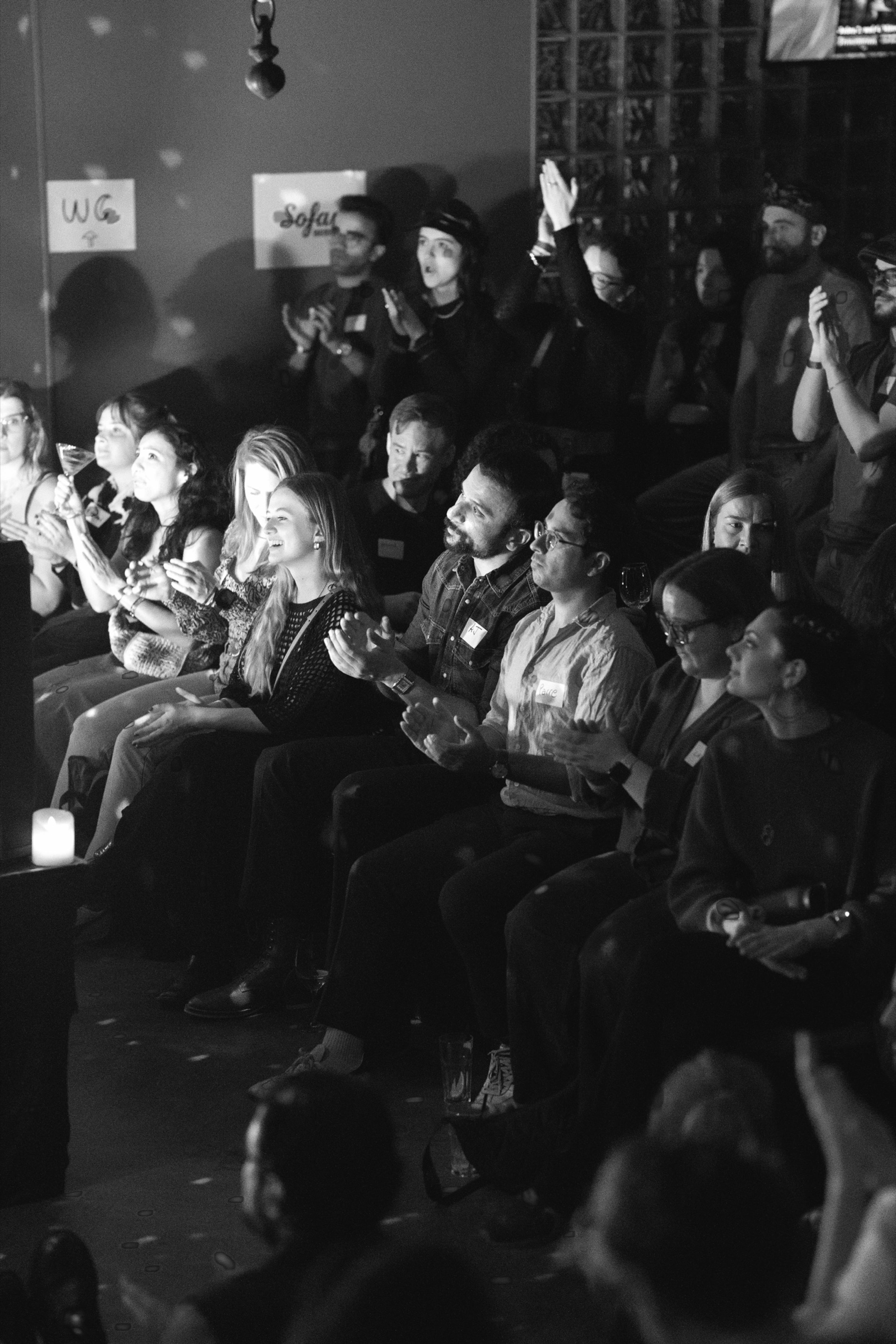 The seated audience applauding beneath the Sofar sign, in black and white
