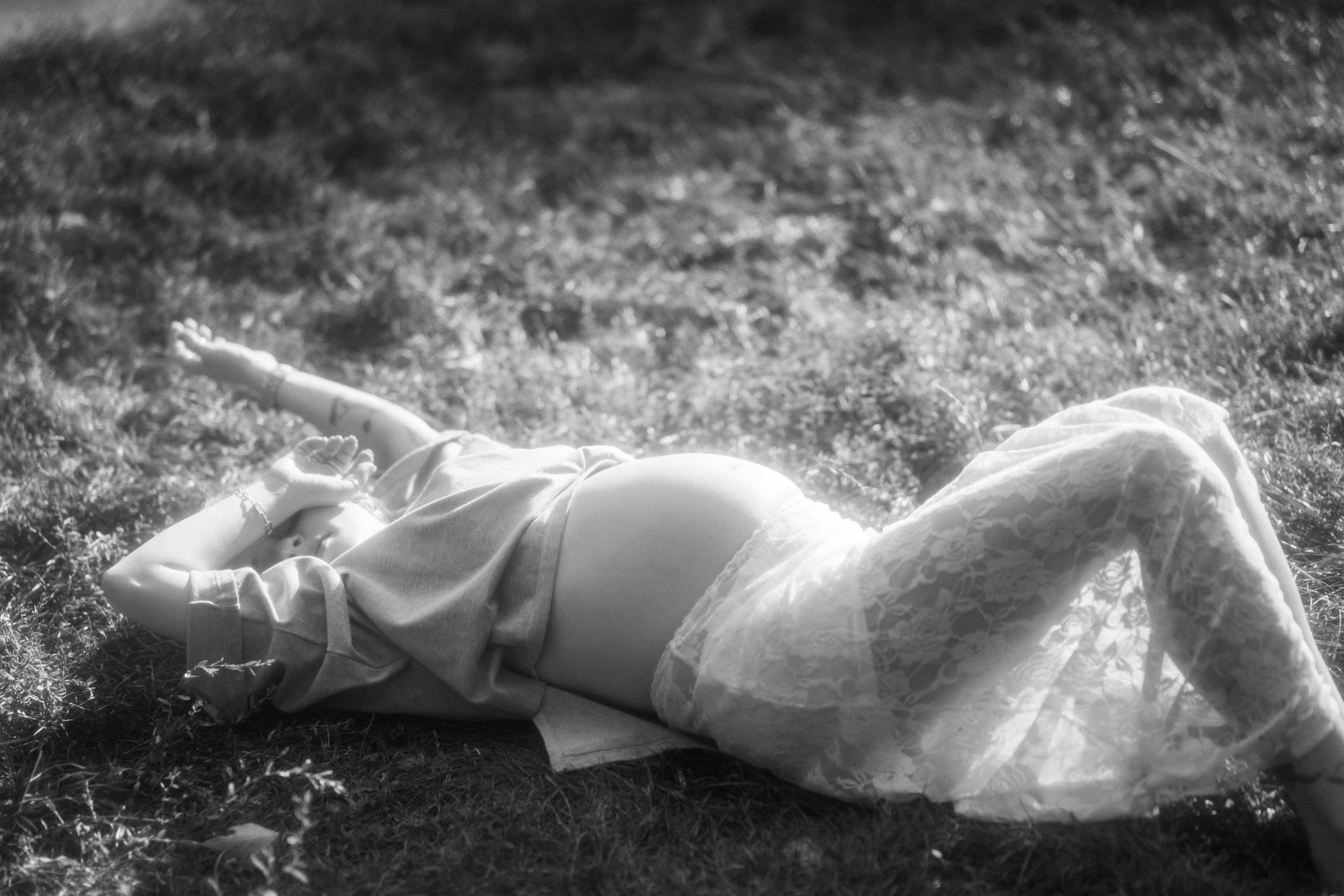 Black-and-white portrait of the expectant mother lying in the grass