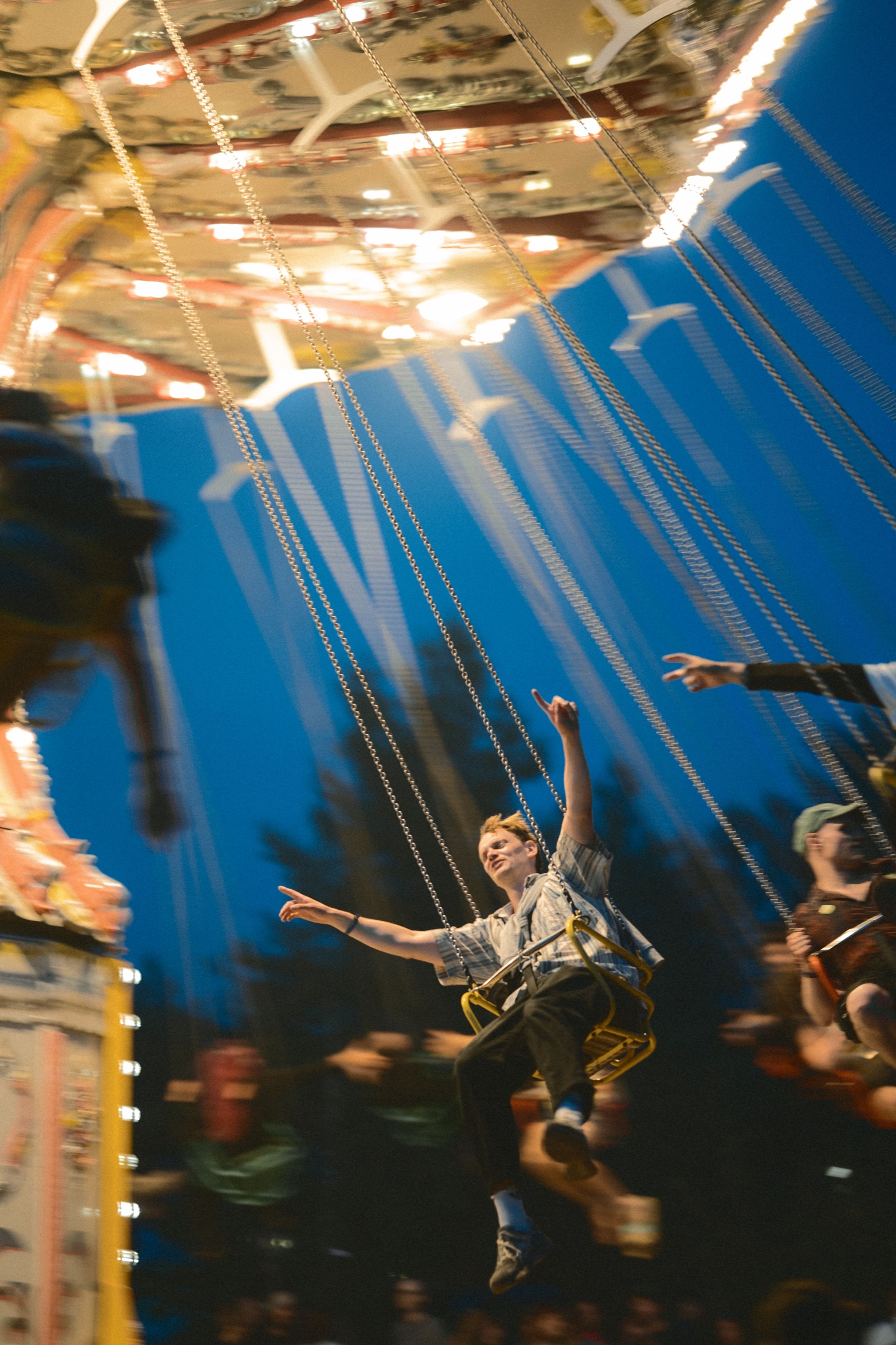 A rider on the swing carousel throwing their arms out at dusk