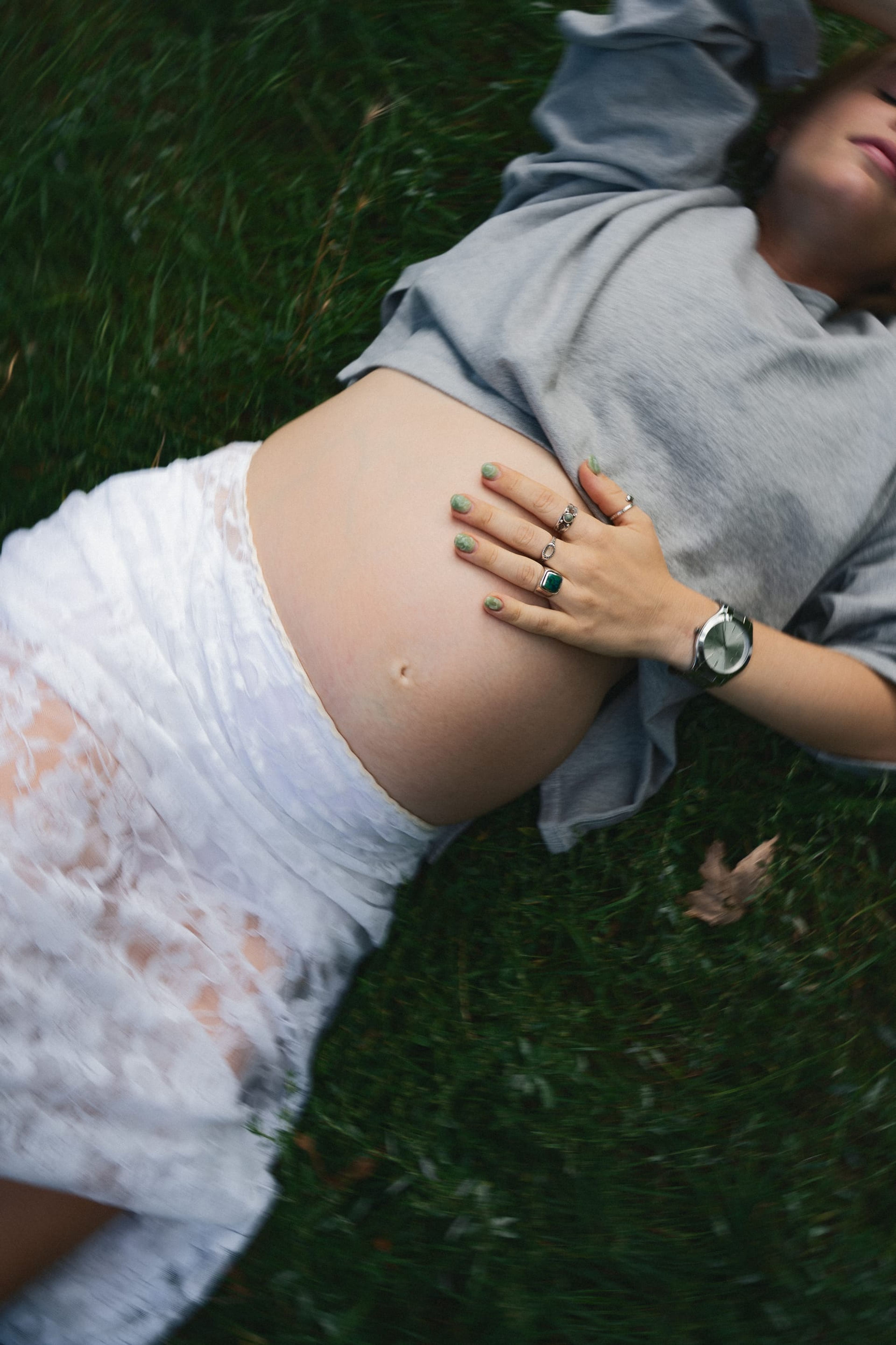 Overhead close-up of the expectant mother's belly, her ringed hand resting on it