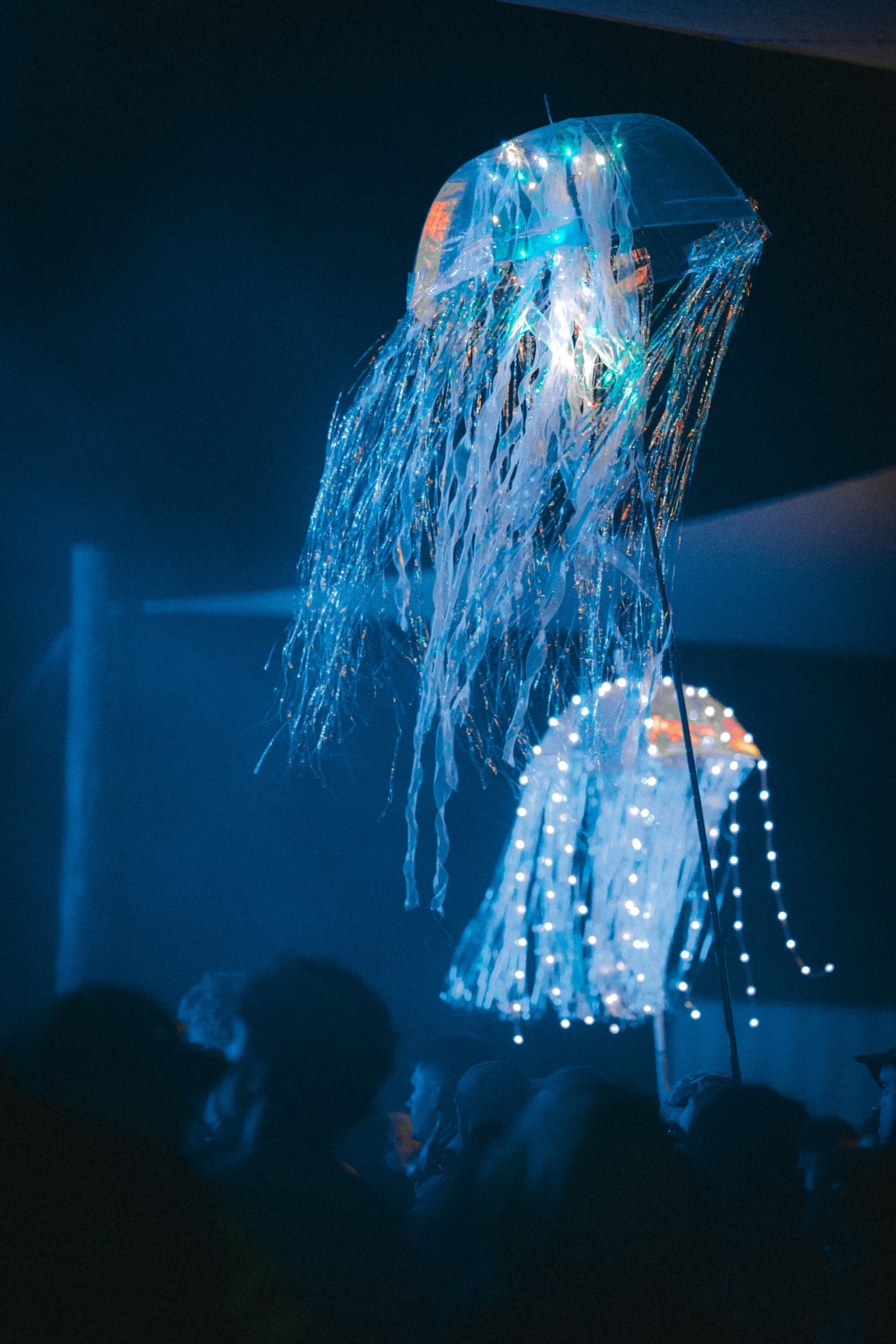 Glowing jellyfish light sculptures floating above the night crowd