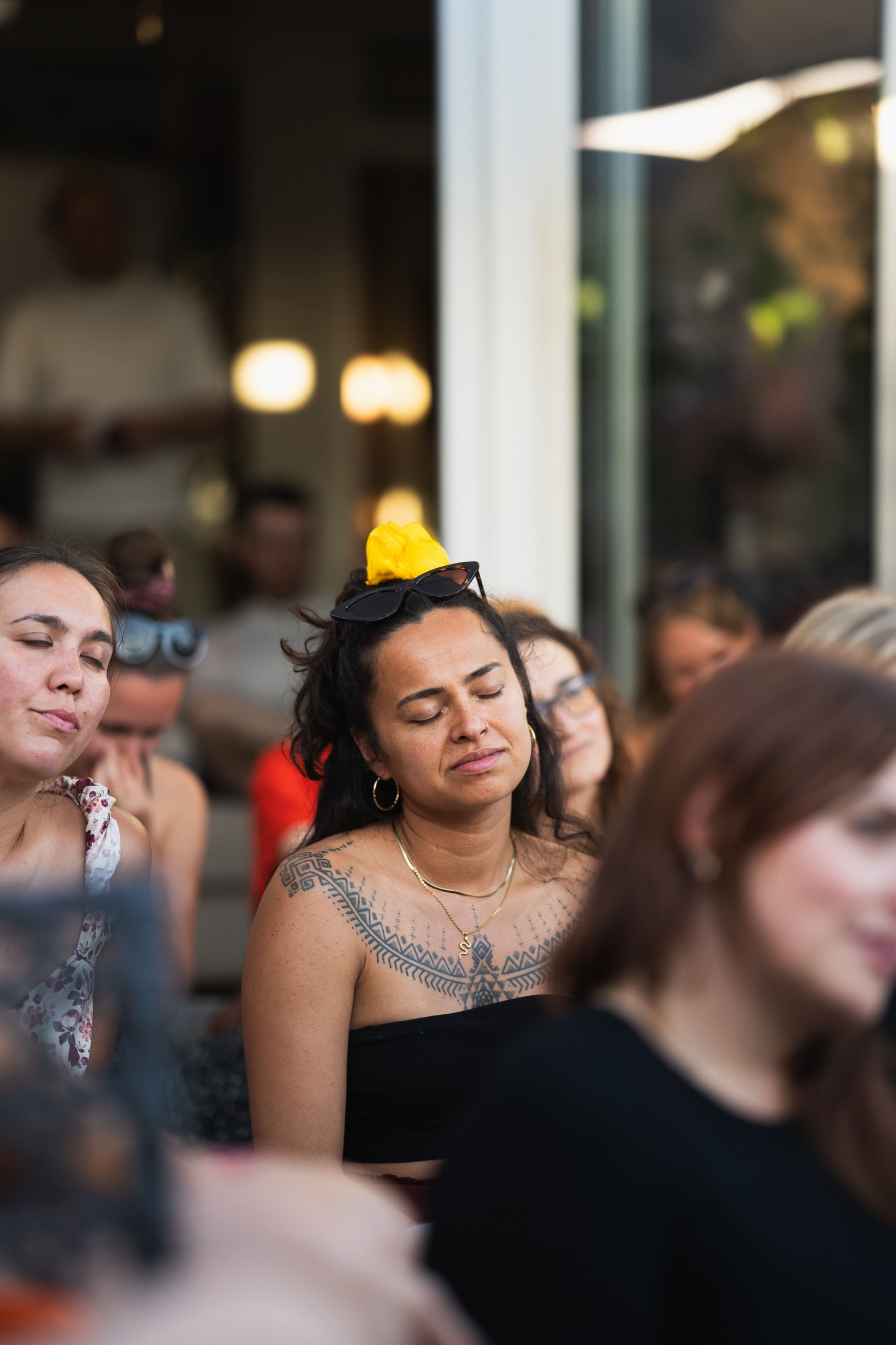 Audience member with a yellow flower in her hair, eyes closed, moved by the music