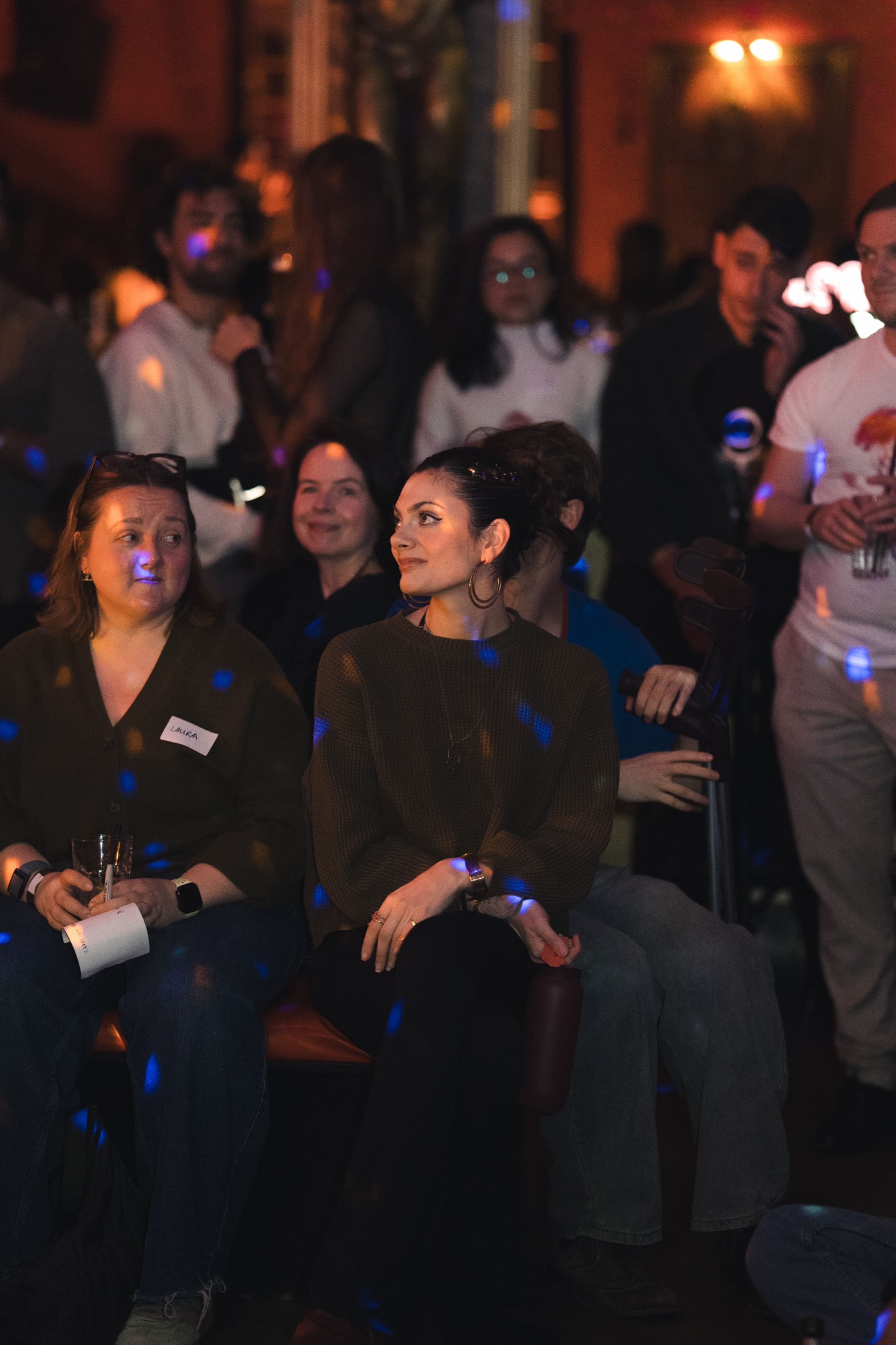 The crowd watching the performance in low, colourful light