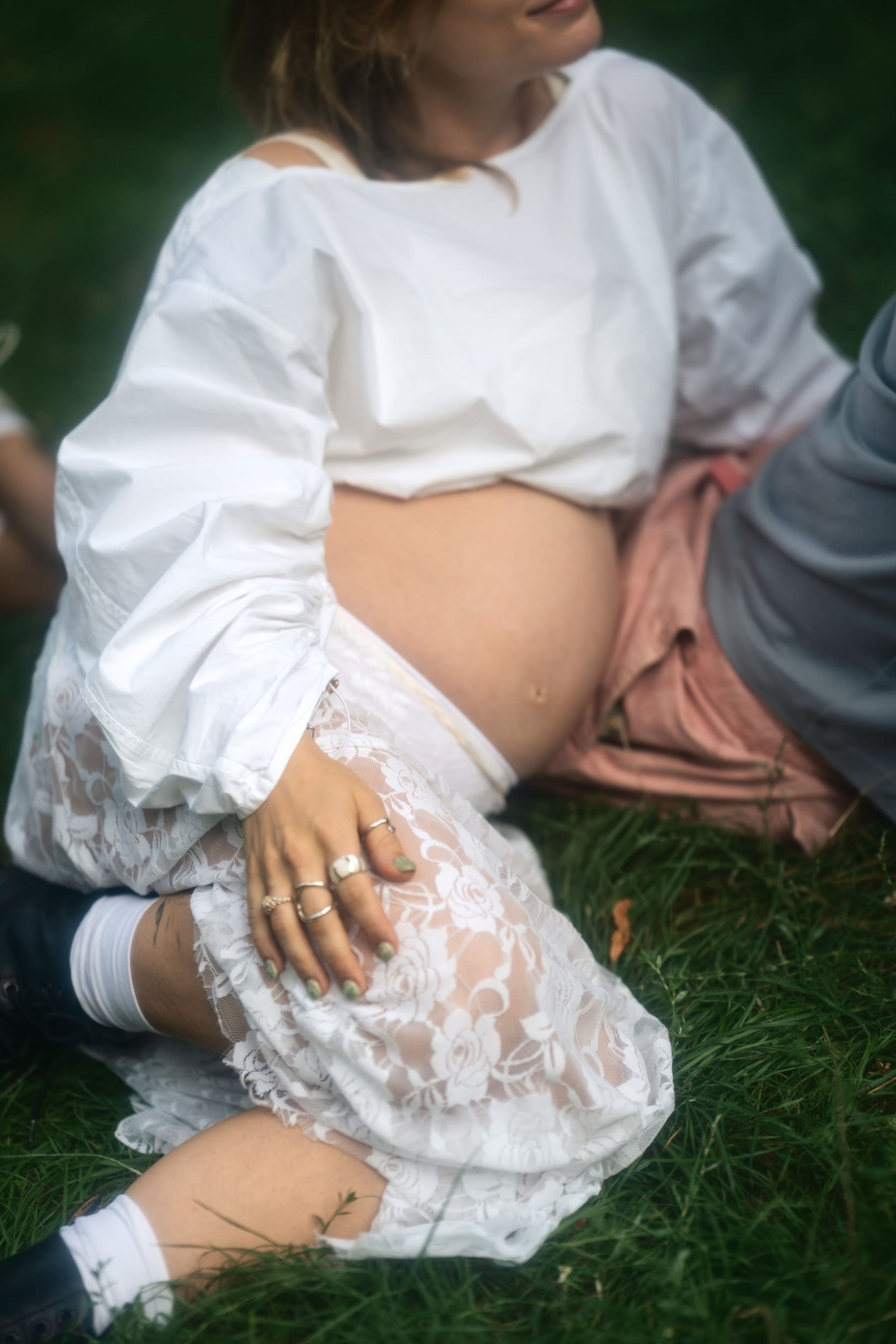 Detail of the expectant couple sitting close, her hand on her belly