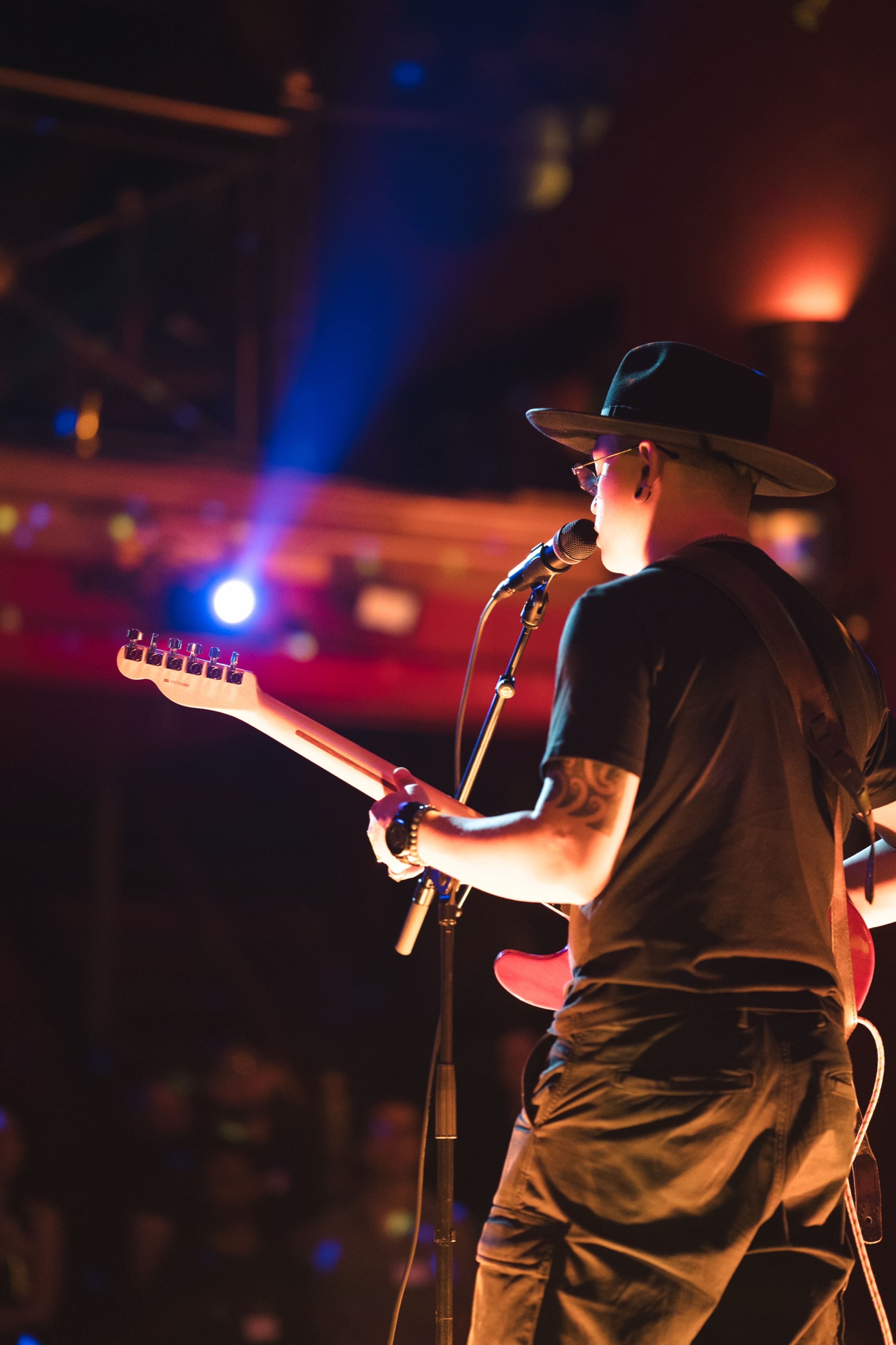 Guitarist at the microphone, seen from behind in blue light