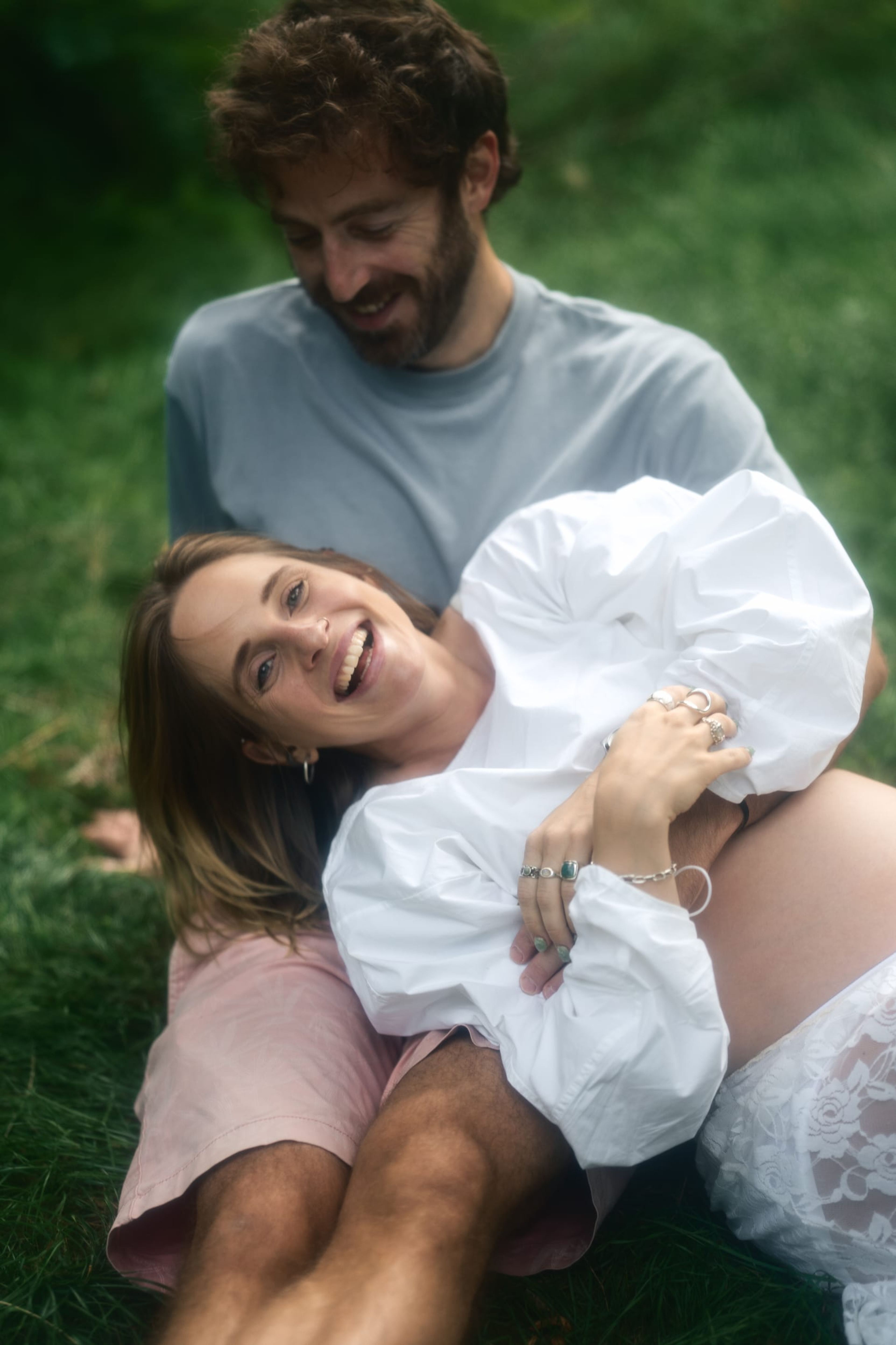 Expectant couple lying close together as she laughs toward the camera