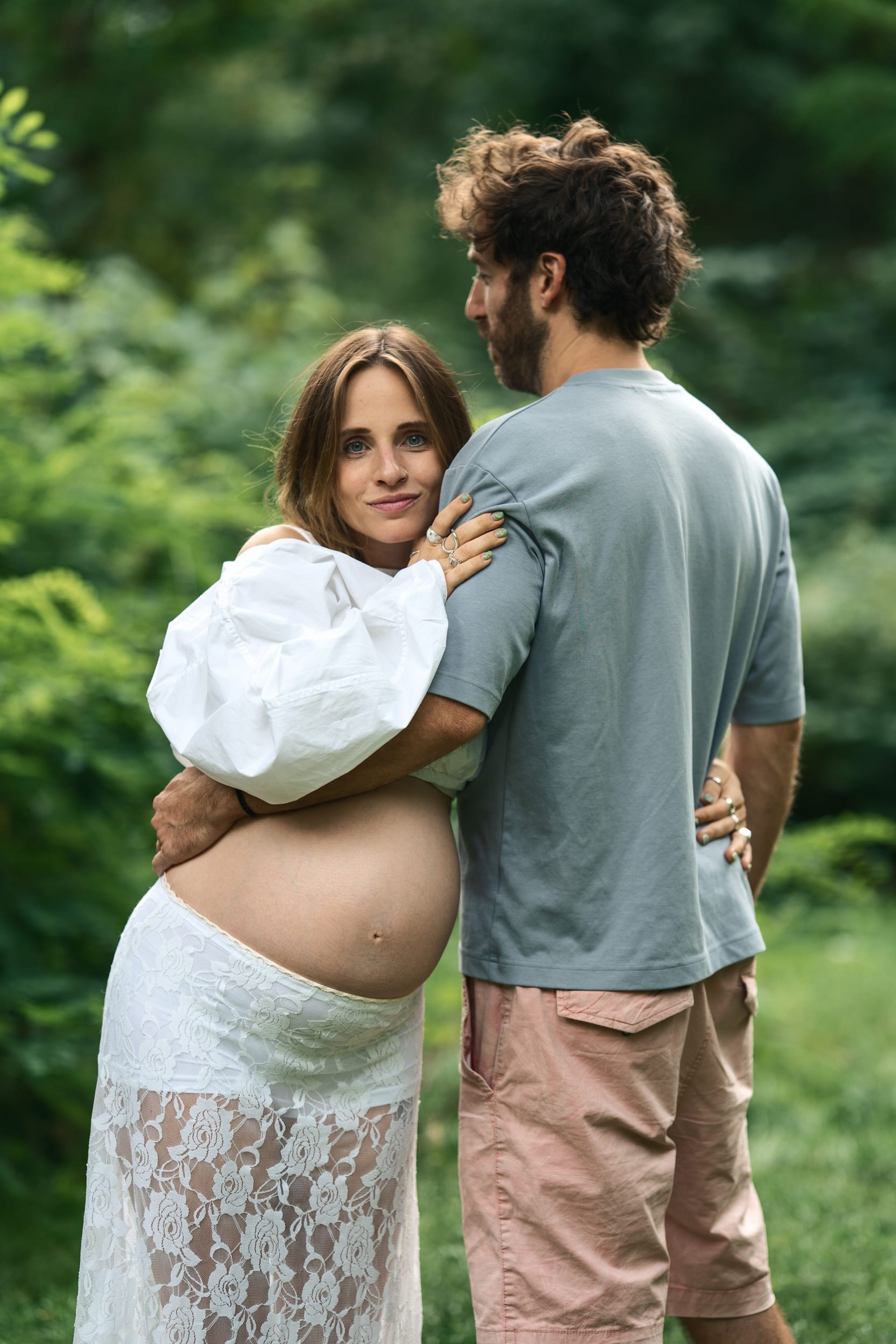 Expectant couple standing close together, her head against him, the bump showing