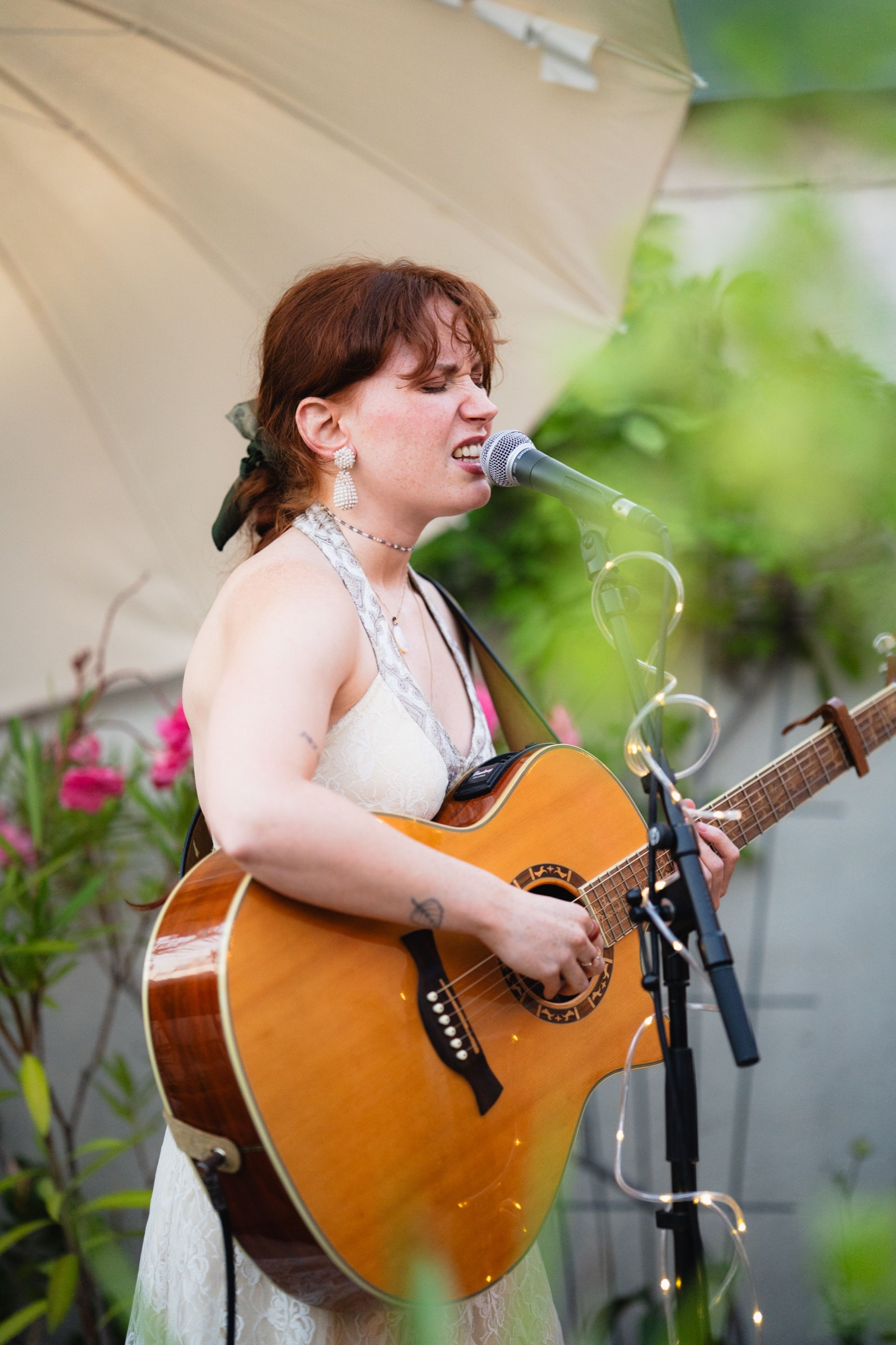Guitarist singing with her eyes closed during her set