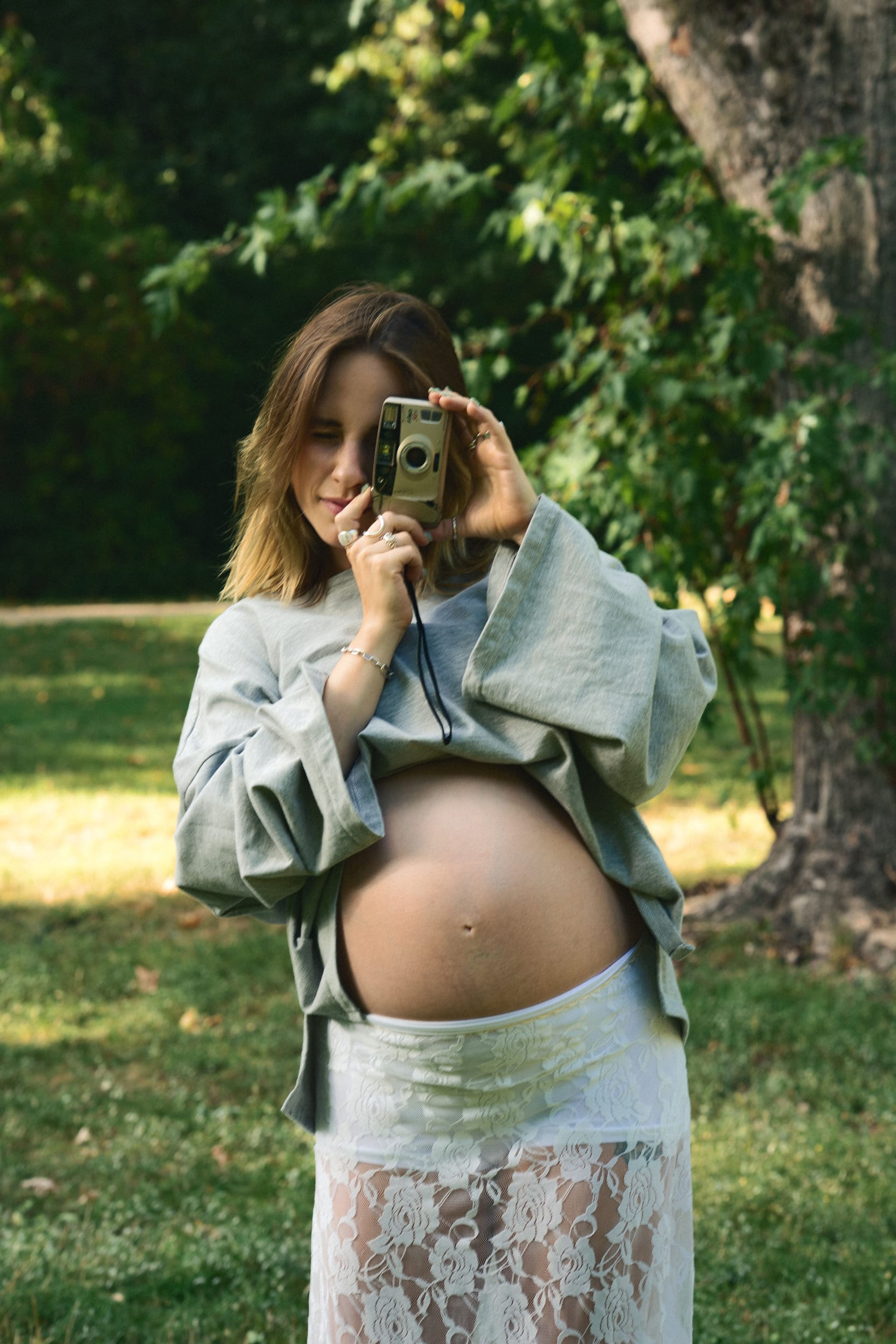 Expectant mother holding a vintage film camera up to her eye