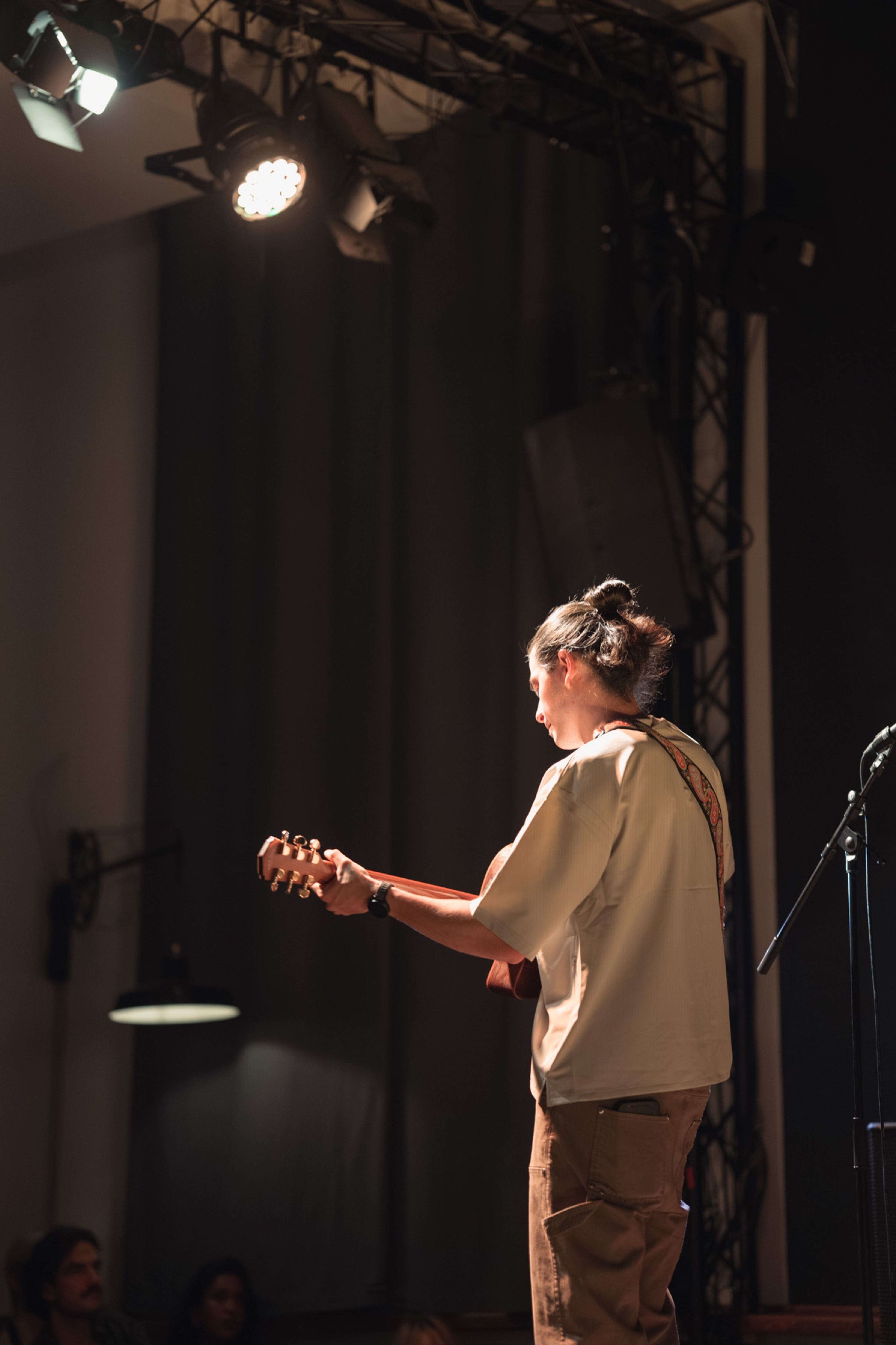 Guitarist under a spotlight on stage, seen from behind